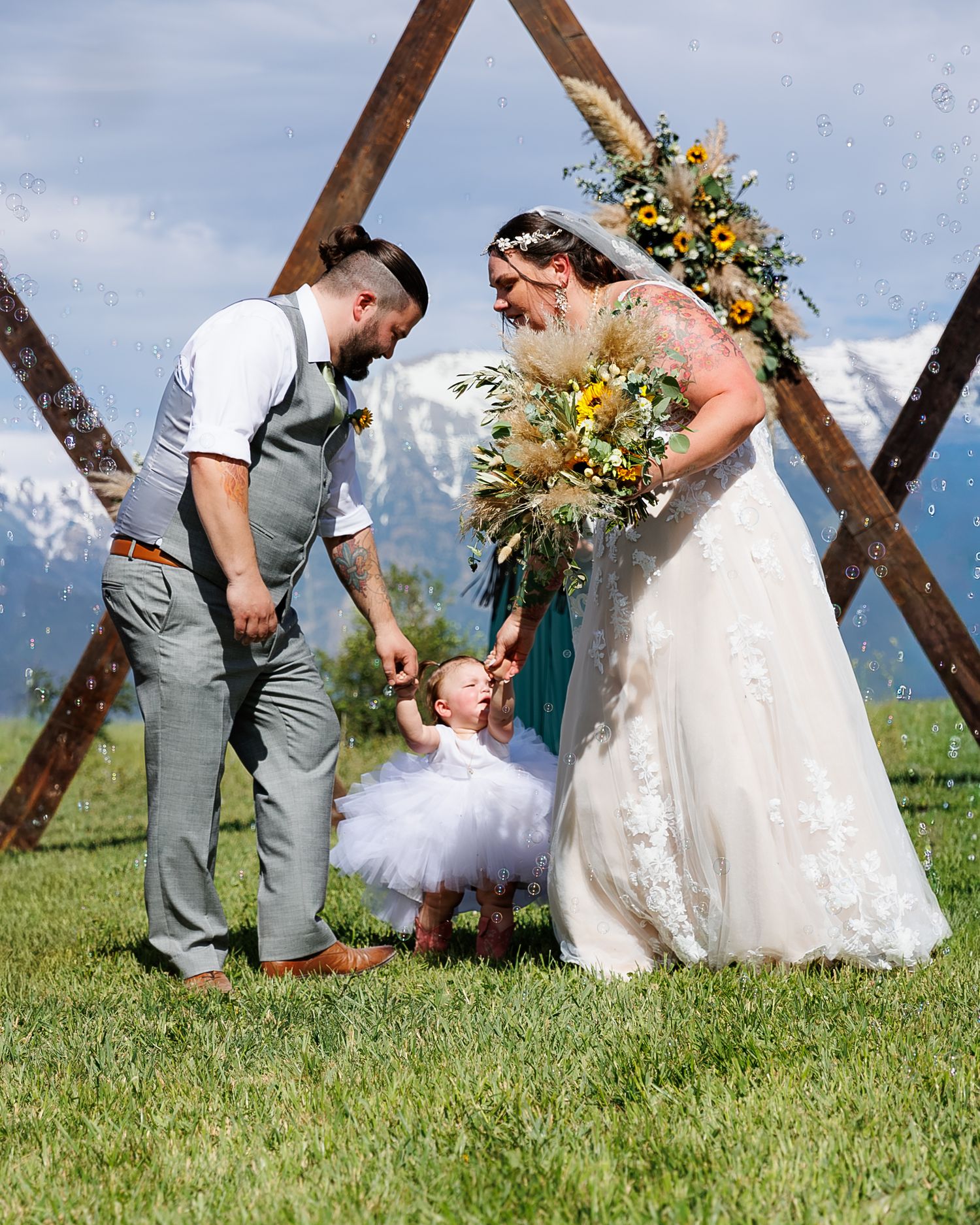 Wedding couple and guests playing lawn games outdoors with wooden beams in the background on a sunny day.