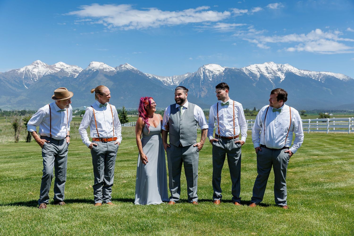 A panoramic sequence of people bending down to examine grass in a green field with mountains in the background.