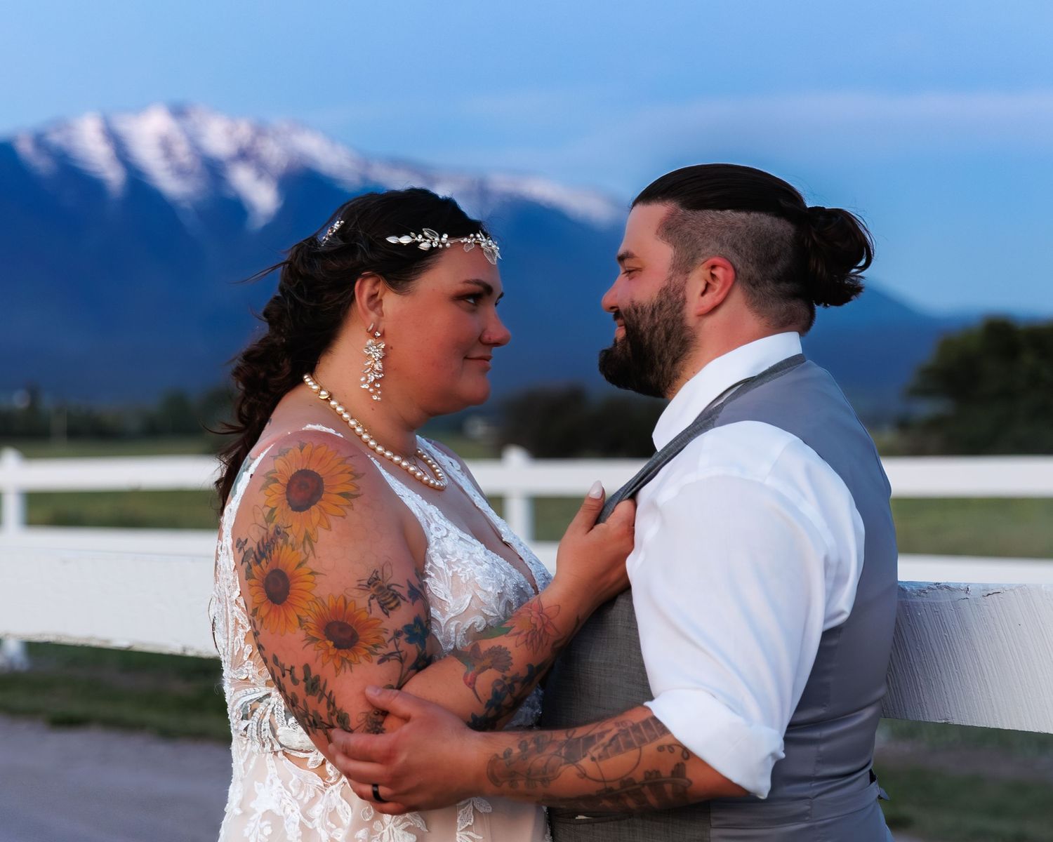 A couple shares an intimate moment during their outdoor wedding photoshoot against a scenic mountain backdrop.
