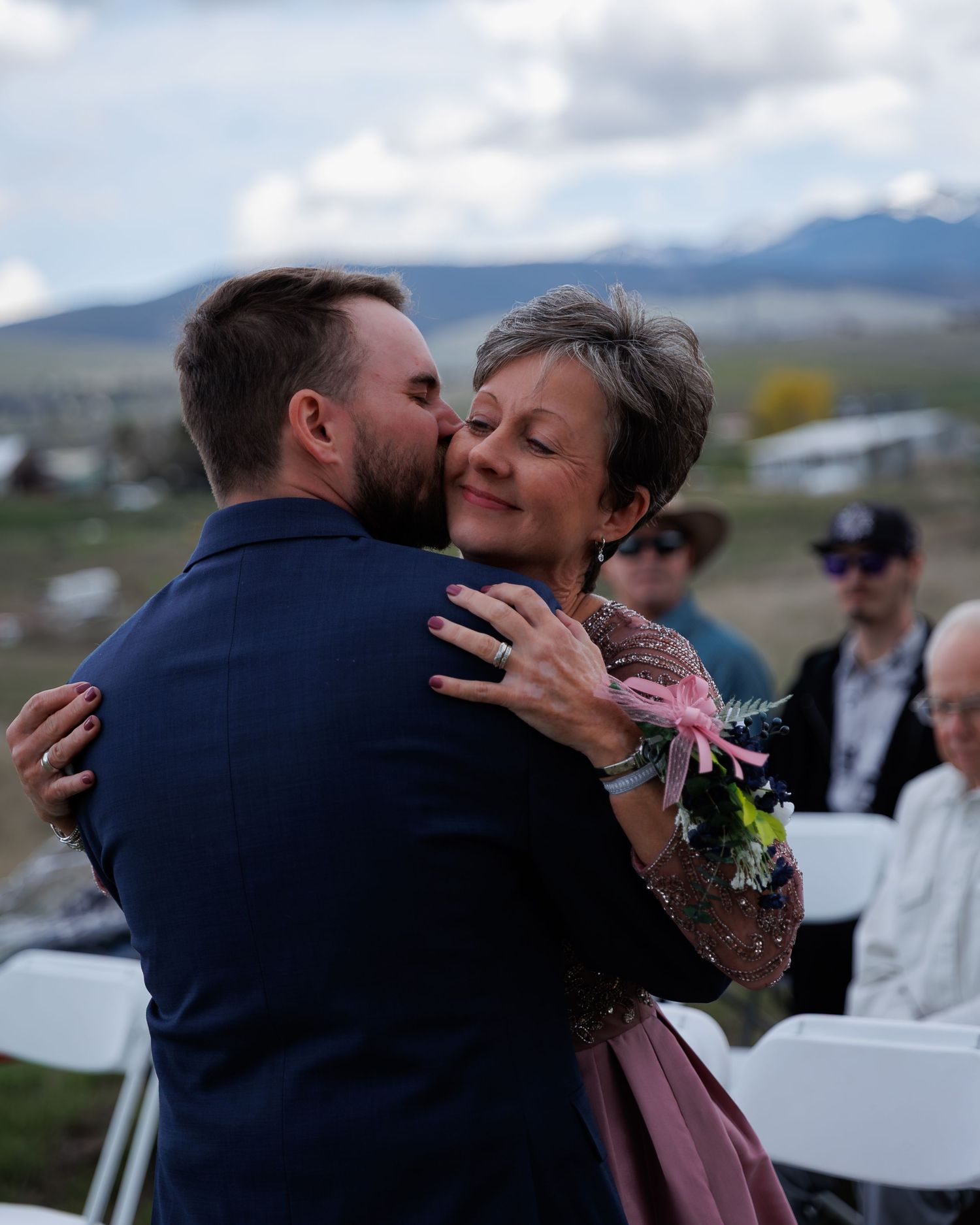 A couple shares an intimate moment during their outdoor wedding reception with mountains in the background.