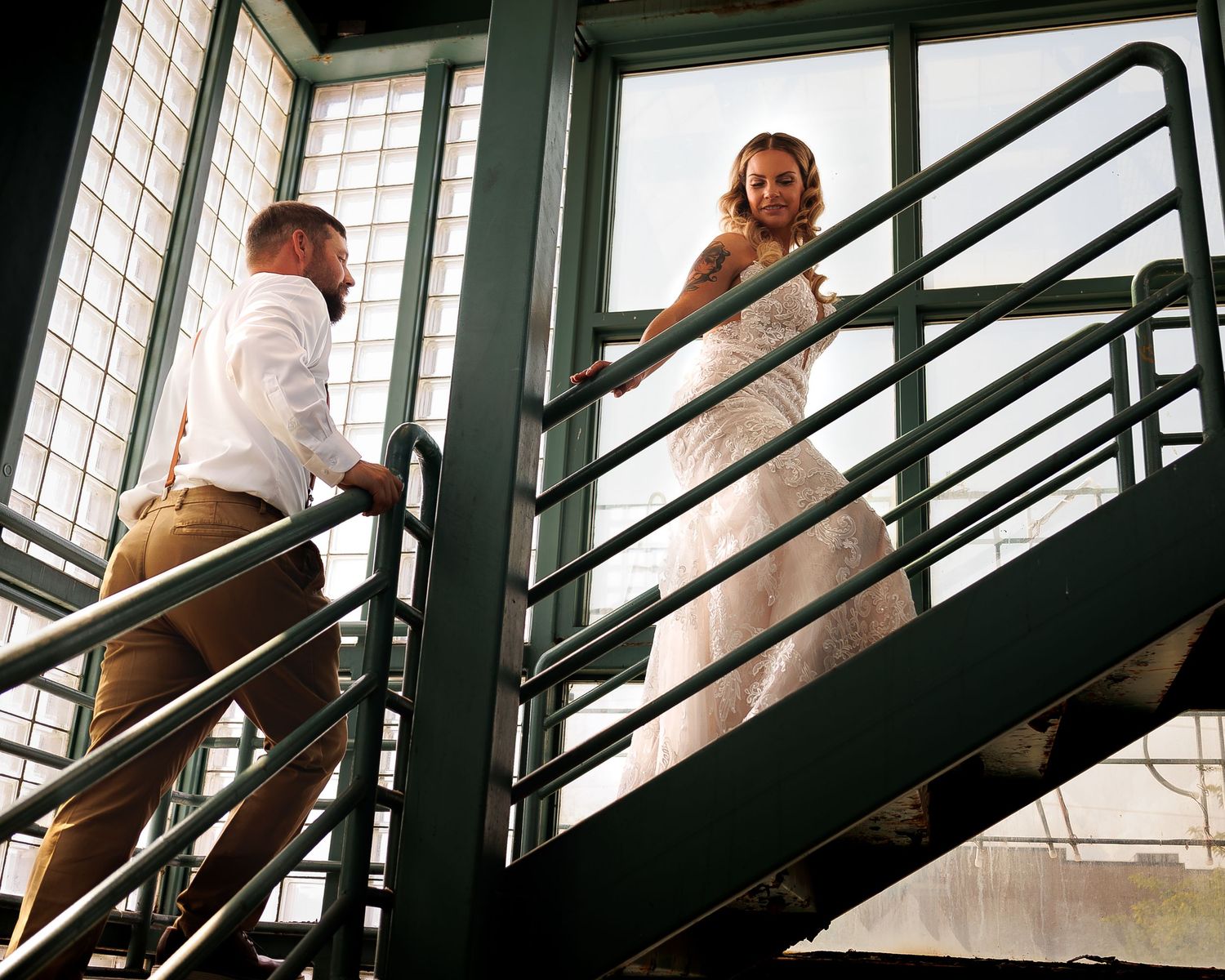 Missoula Bride and Groom walk up a modern staircase with dramatic shadows and geometric lines cast by metal railings.