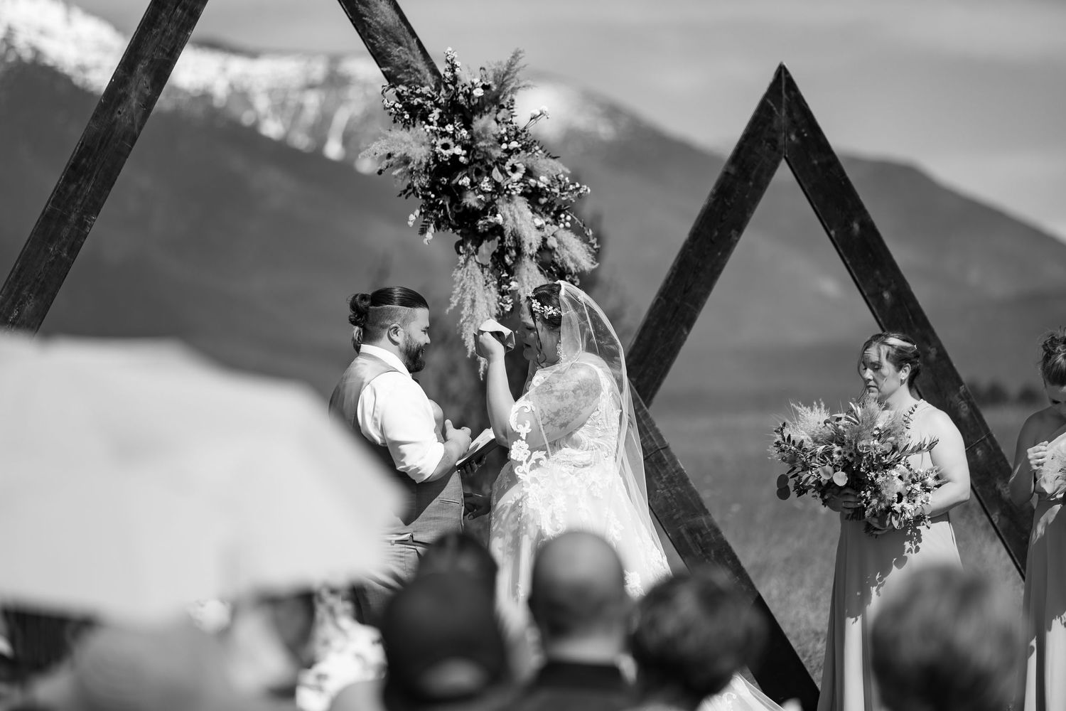 A black and white panoramic collage of wedding moments showing bouquets, rings, and celebration details.