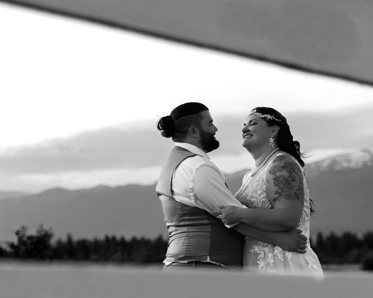 A series of black and white images showing silhouettes of two people kissing against scenic mountain landscapes.