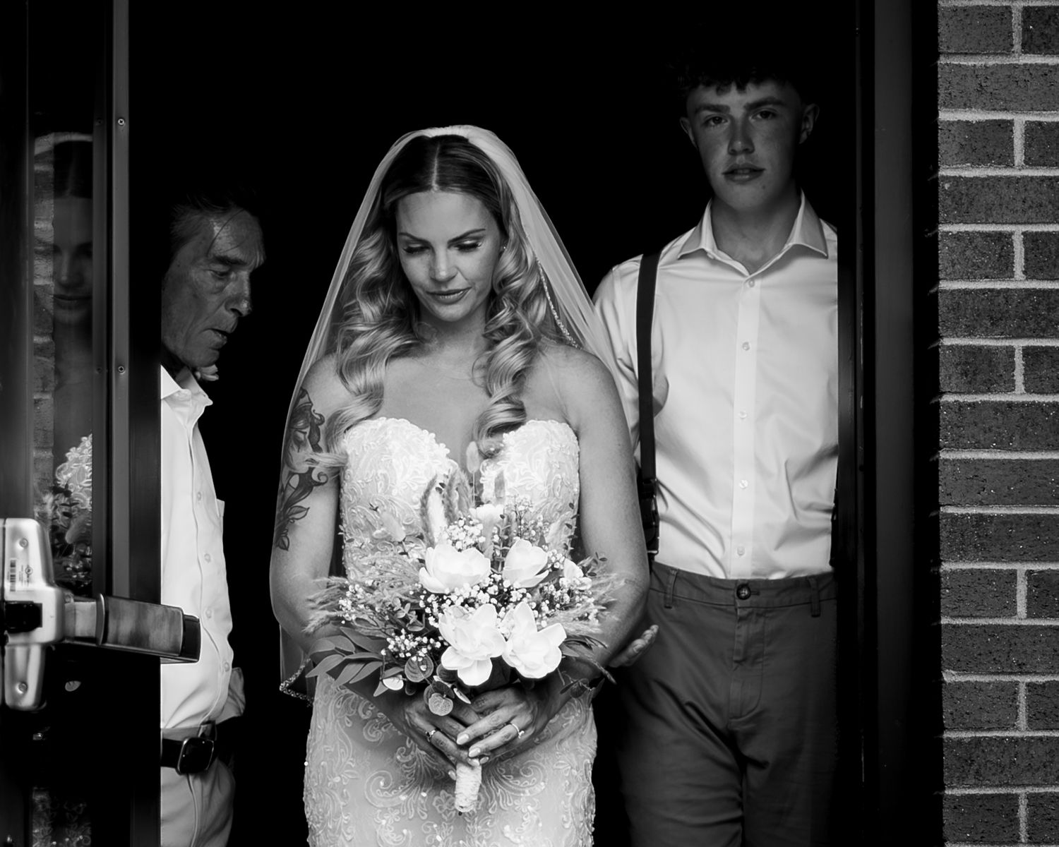 Black and white style wedding photography show bride and bridal party members standing against brick walls in downtown Missoula Montana