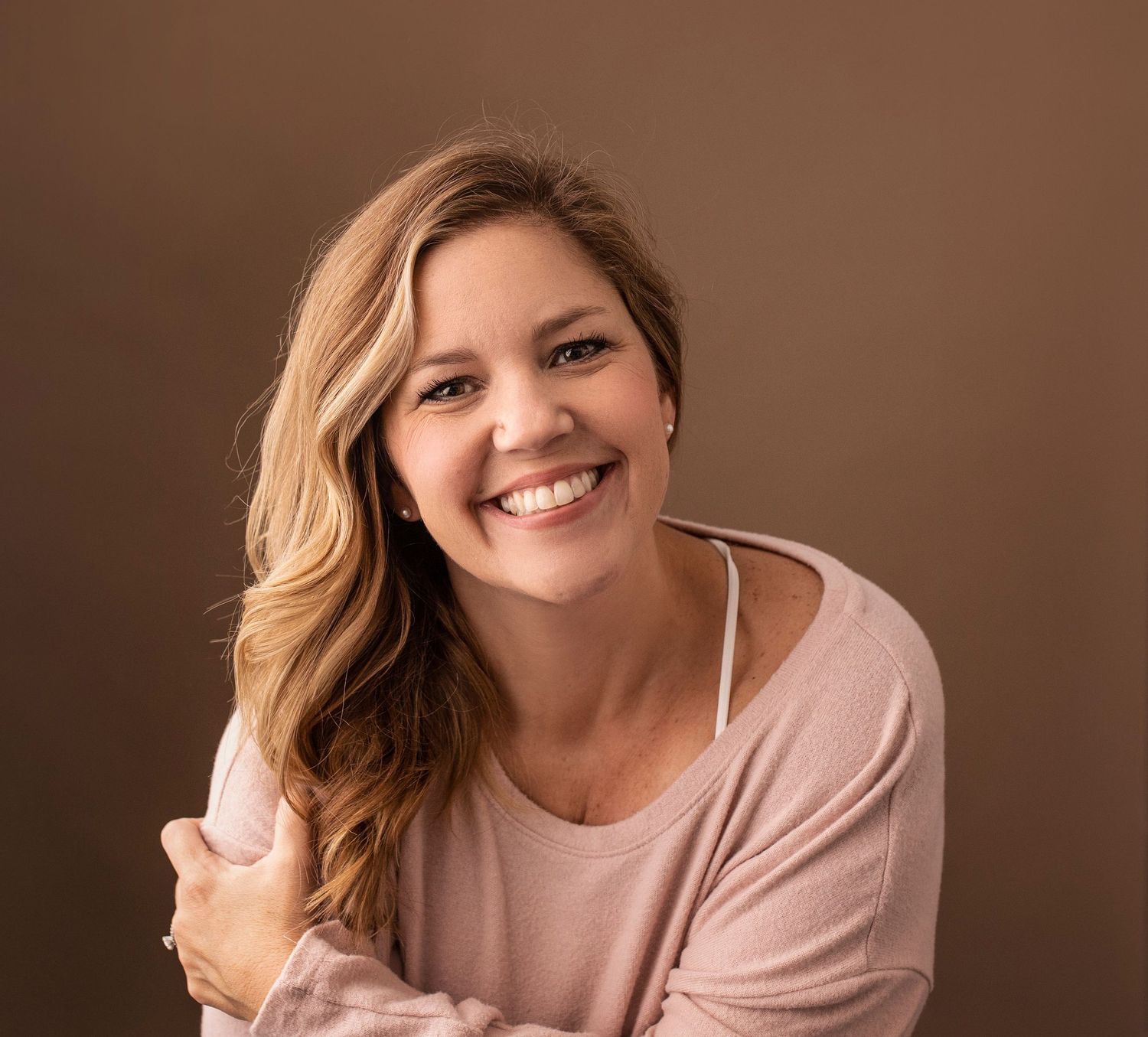 Headshot photos showing someone in pink smiling warmly against a brown background for professional portraits.