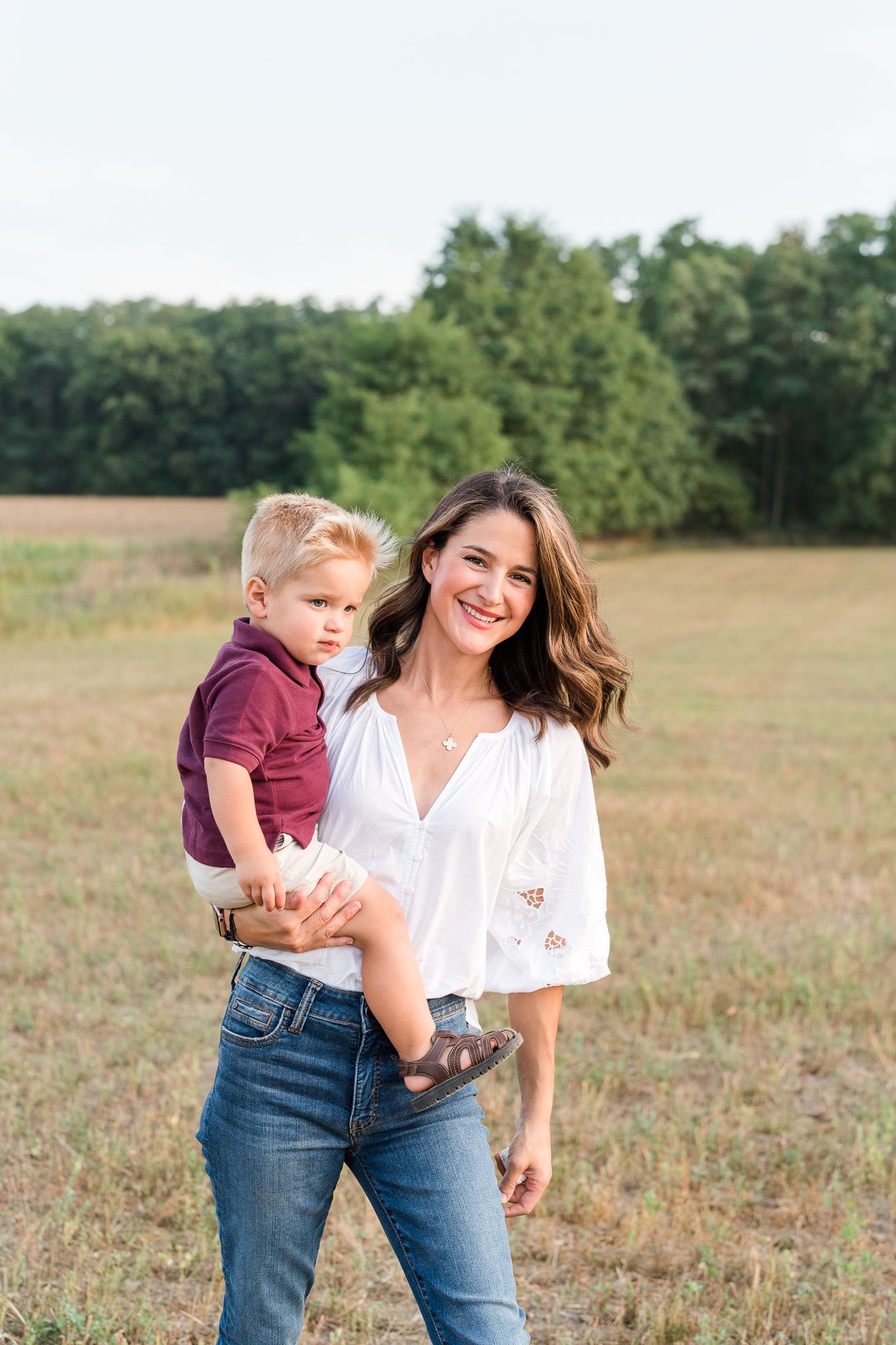 Casual outdoor family photography session in a sunlit field with natural poses.