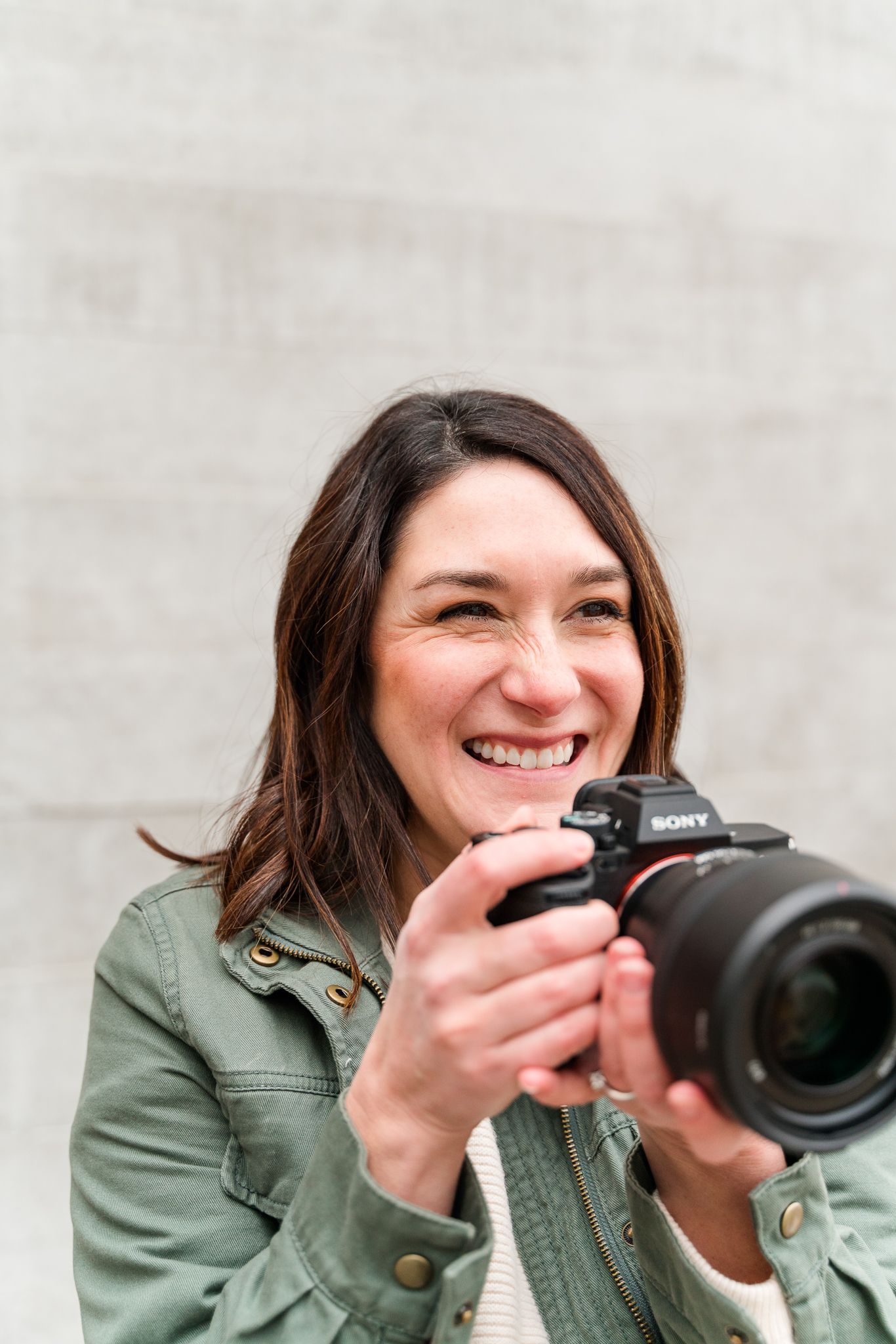 Photographer in green jacket demonstrates camera techniques in professional headshots.