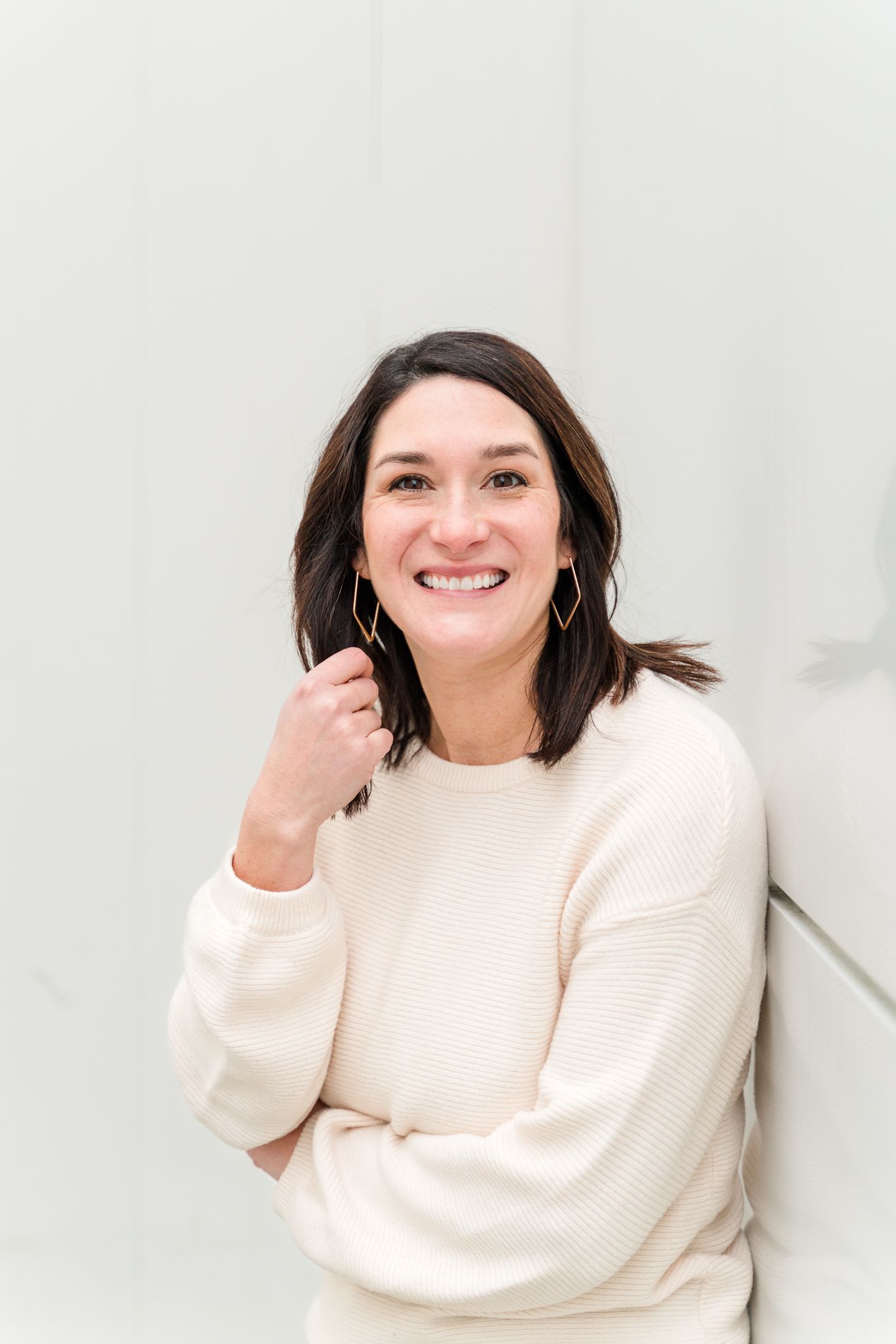 Portrait series against white background showing joyful expressions in cream sweater.