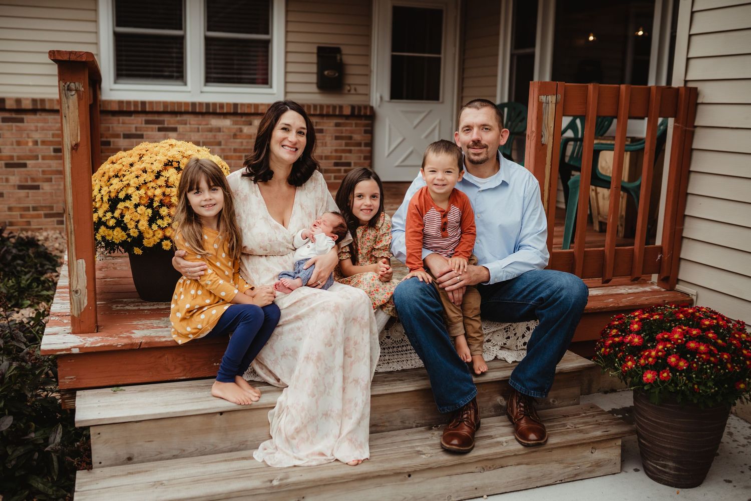 Candid family portrait on rustic porch with autumn decor.