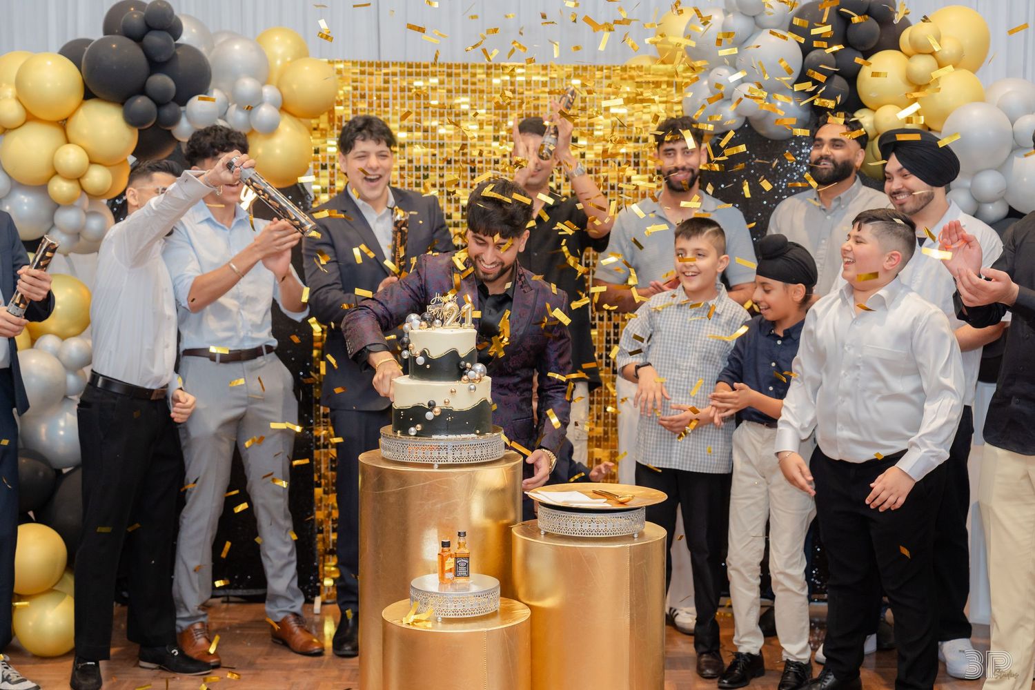 Wedding guests celebrate with black and gold balloons during an elegant indoor reception party.