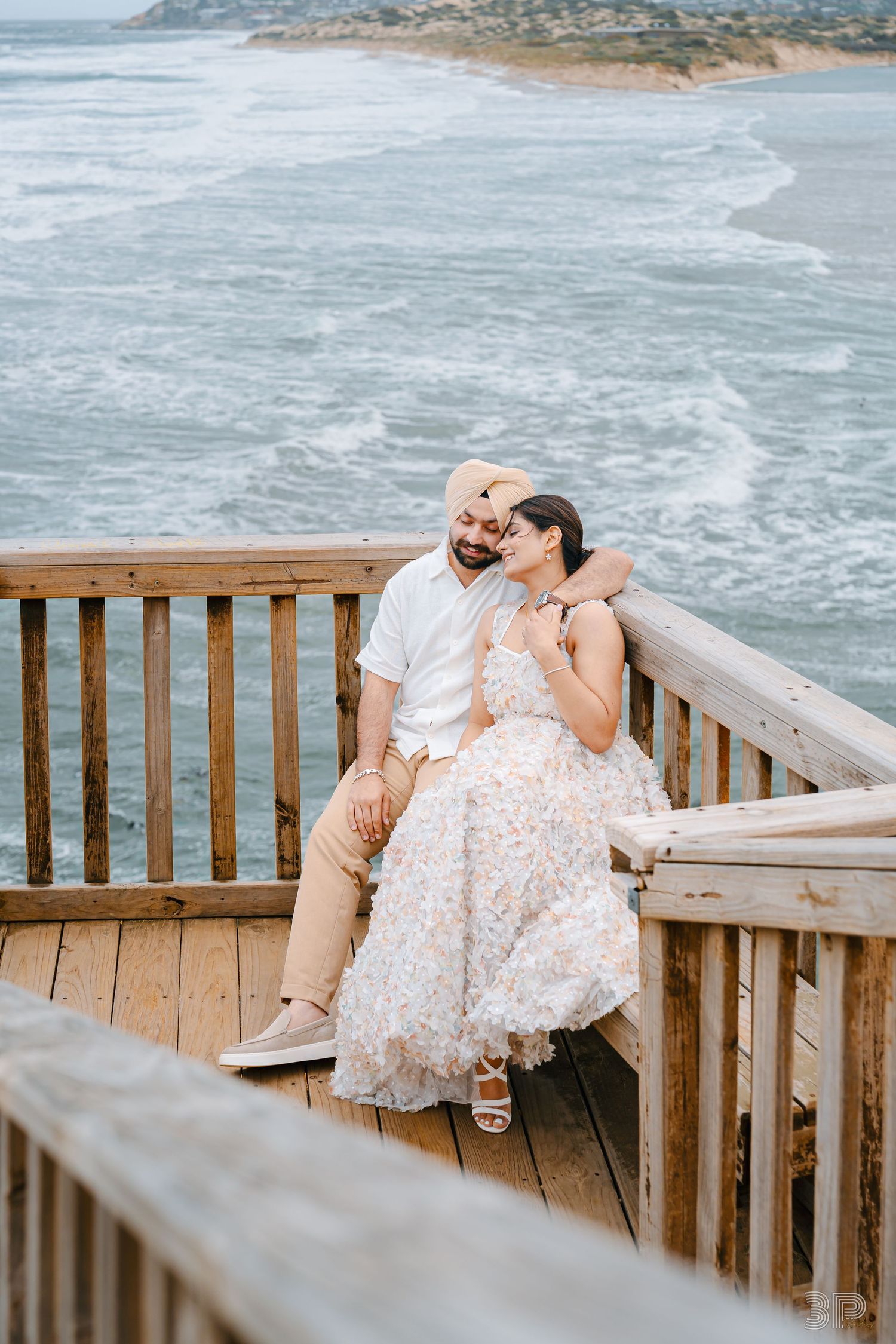 Couple enjoying a romantic moment on a wooden deck overlooking a dramatic coastal ocean view.