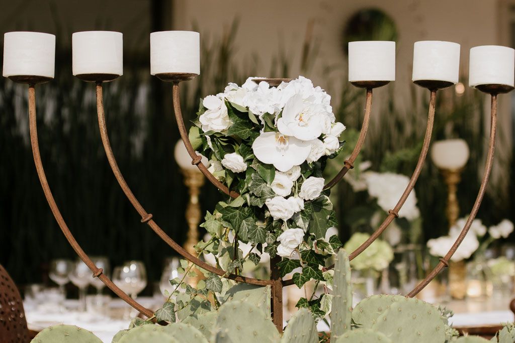 White rose floral centerpiece with curving branches creates an elegant tablescape for a wedding reception.