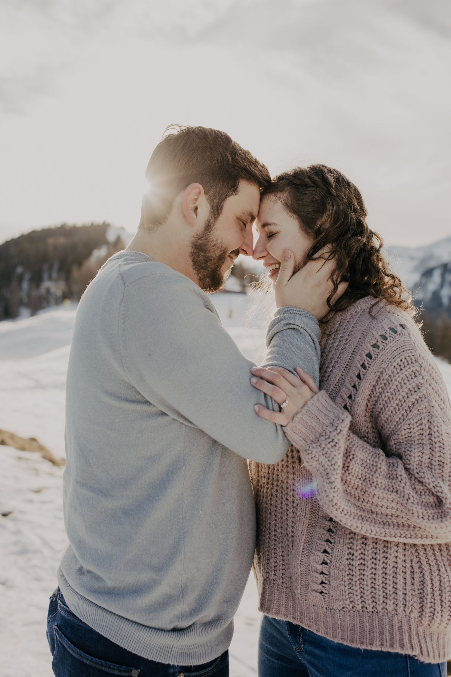 Intimate couple's portrait in winter mountain setting with sunlight.