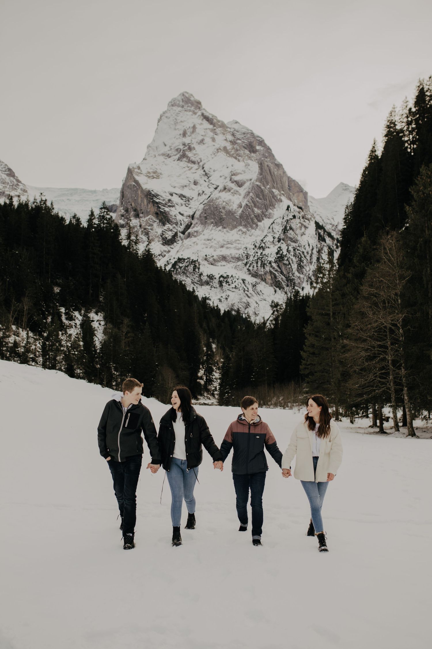 Group walking together through snowy mountain valley with peaks in background.