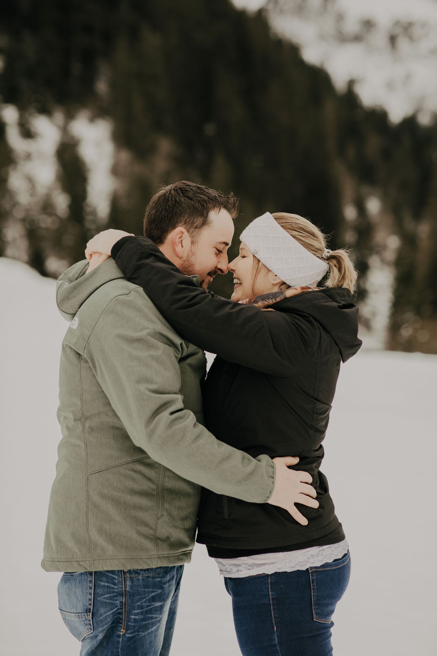 A romantic winter embrace between two people wearing coats in a snowy outdoor setting.