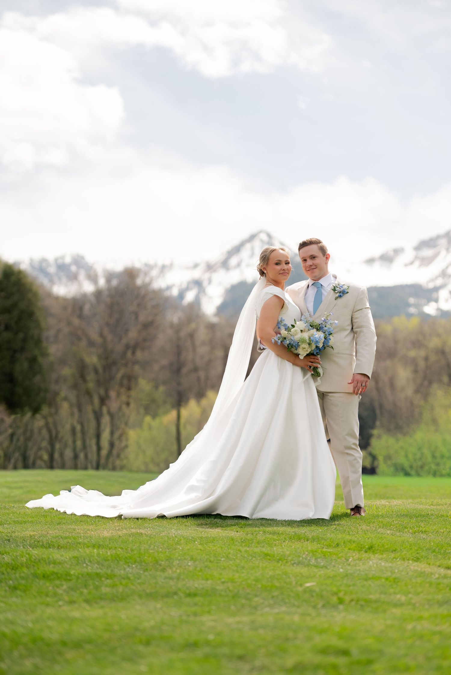 bridal photos in the green fields of provo Utah with the snow capped mountains in the background