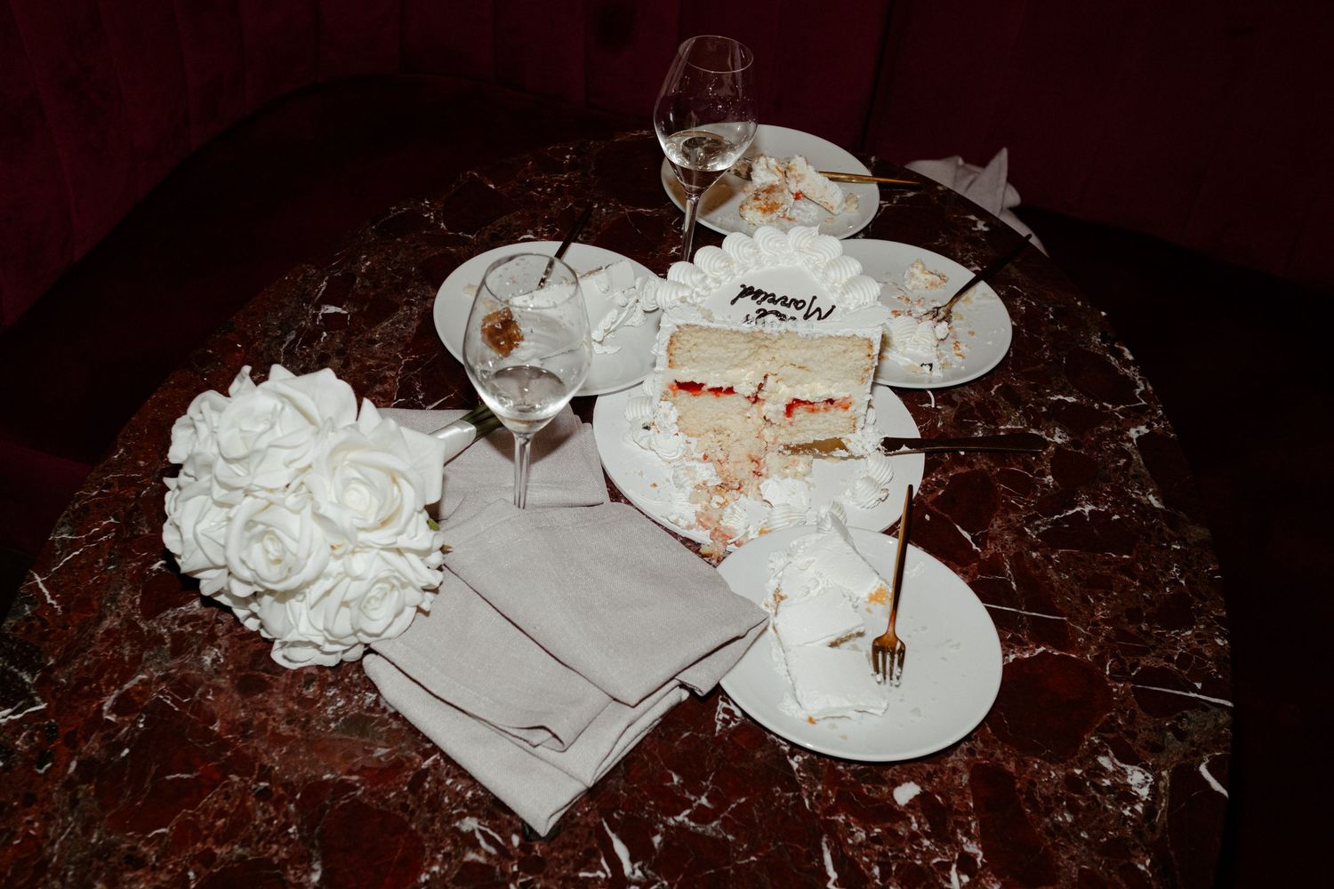 Wedding reception details with champagne glasses and cake on marble table.