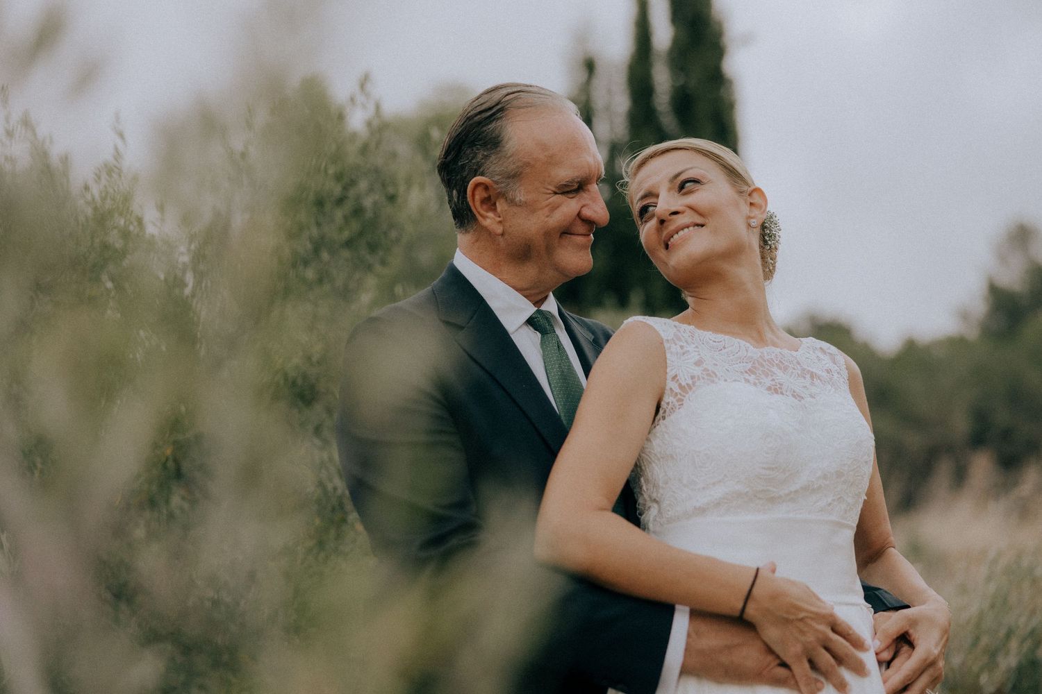 Happy couple embraces during outdoor wedding photoshoot with cypress trees in background. Wedding photographers Cyprus, Paphos, Limassol.