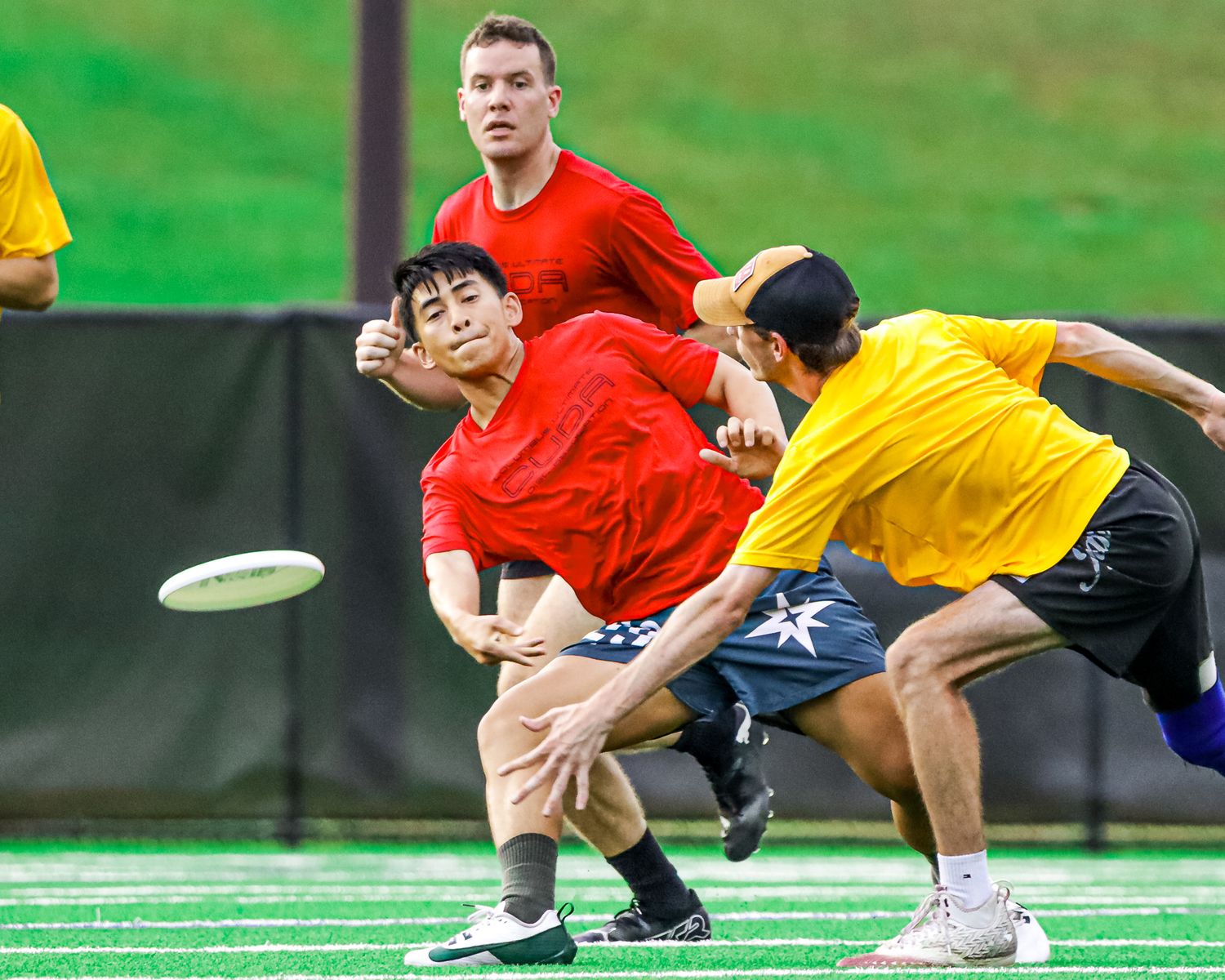 Athletes compete in an intense wrestling match on a green mat during a sports competition.