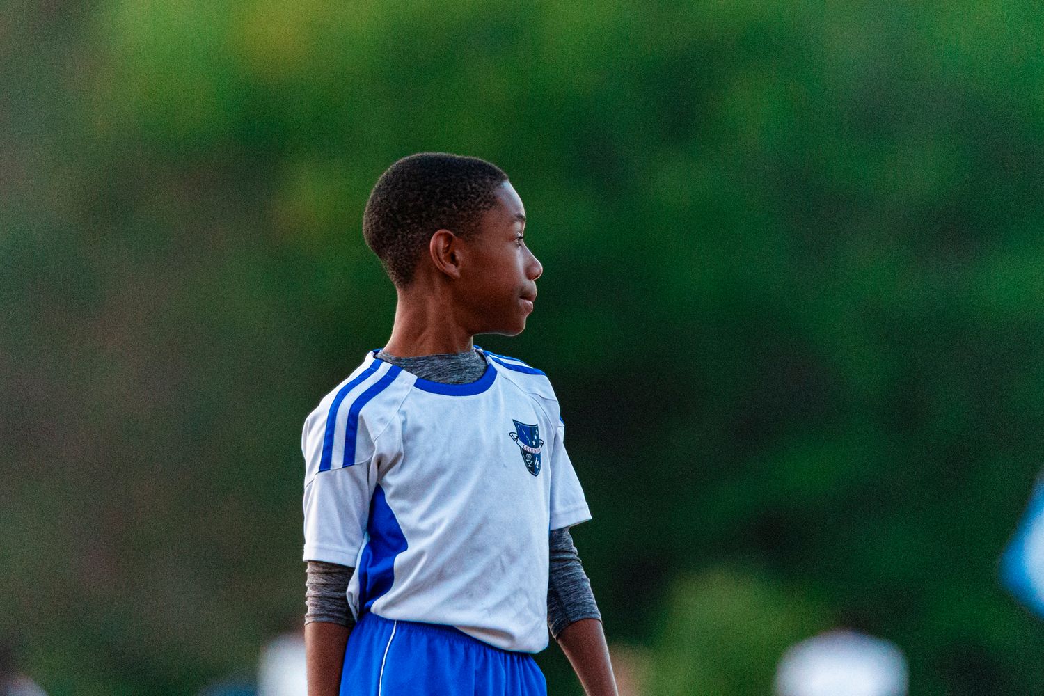 Soccer players in blue and white uniforms line up during a youth sports match on a sunny day.