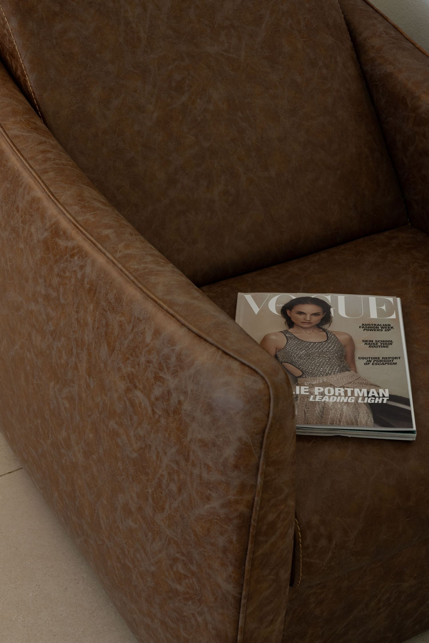 A Vogue magazine sits on a brown textured surface with dramatic lighting and shadows.