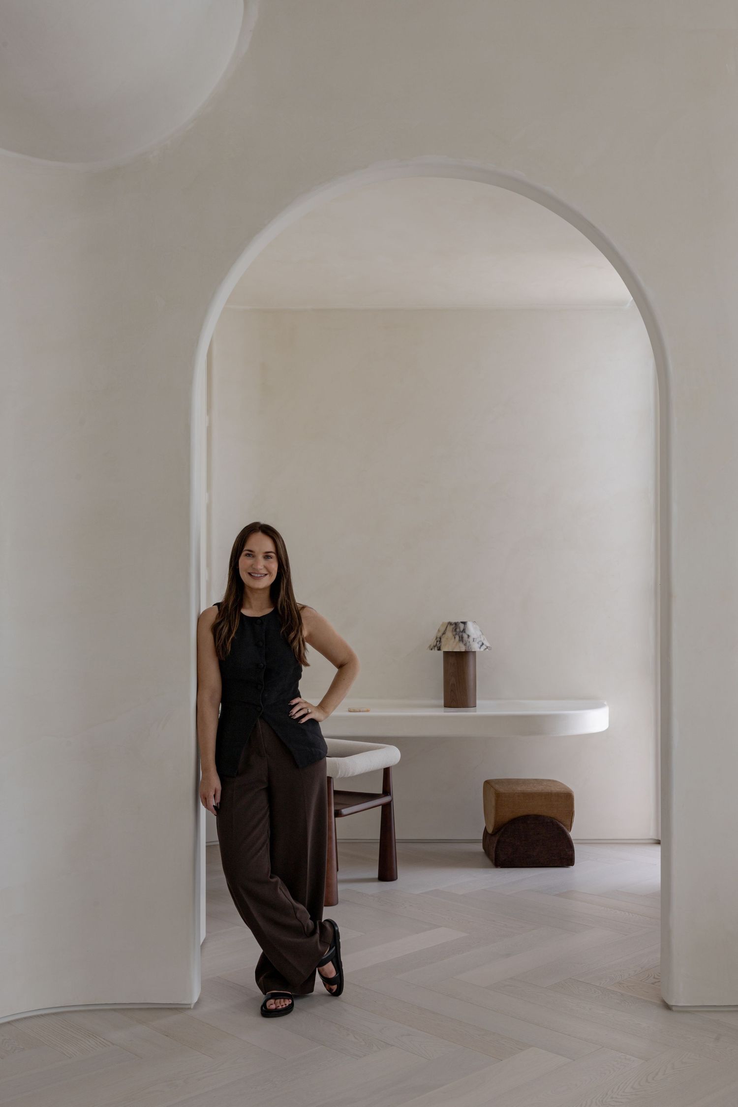 Minimalist white interior space with curved archways and built-in shelving creates a serene architectural atmosphere.