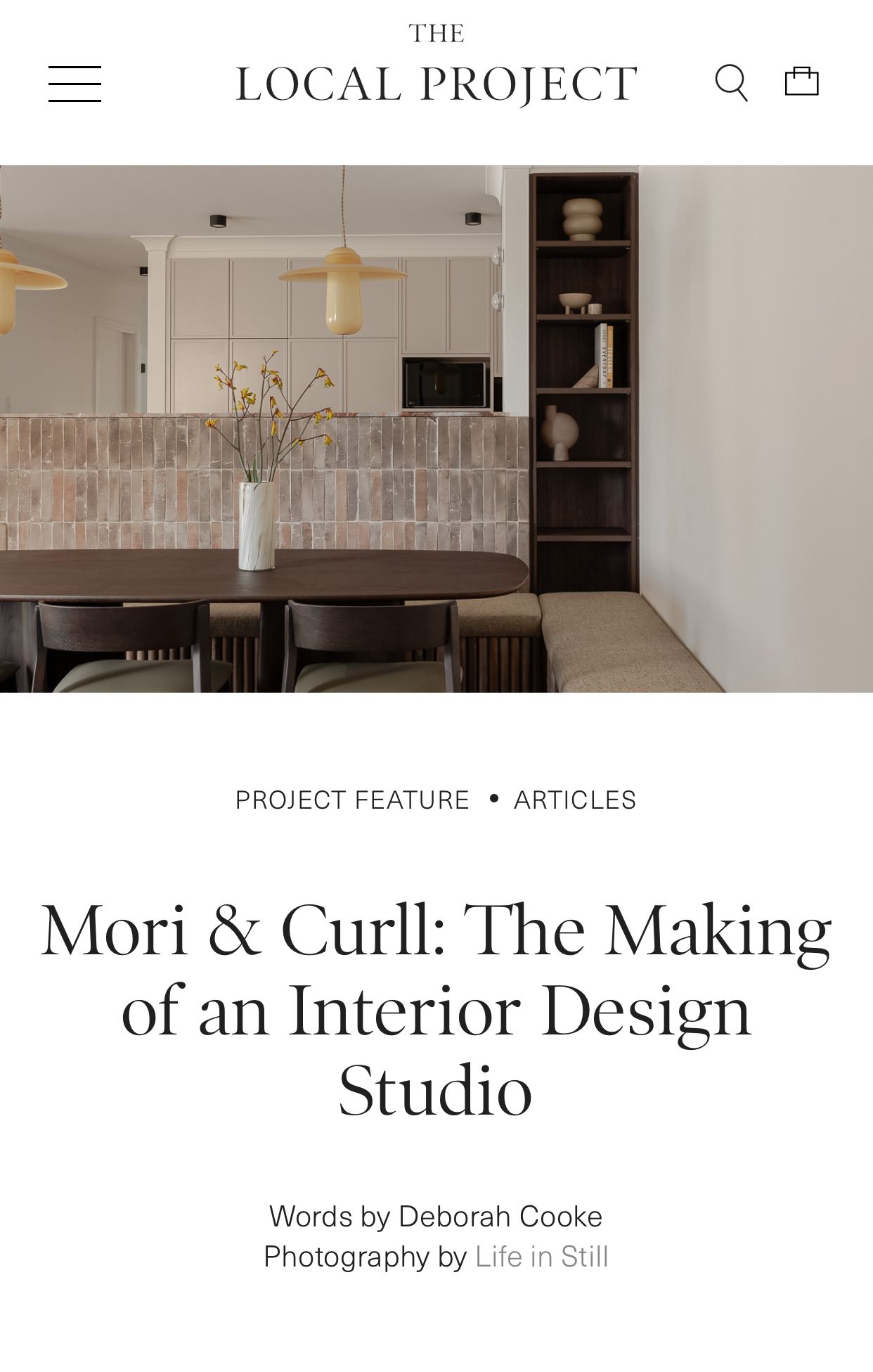 Modern interior design studio website header showing minimalist dining area with wooden chairs and pendant lighting.