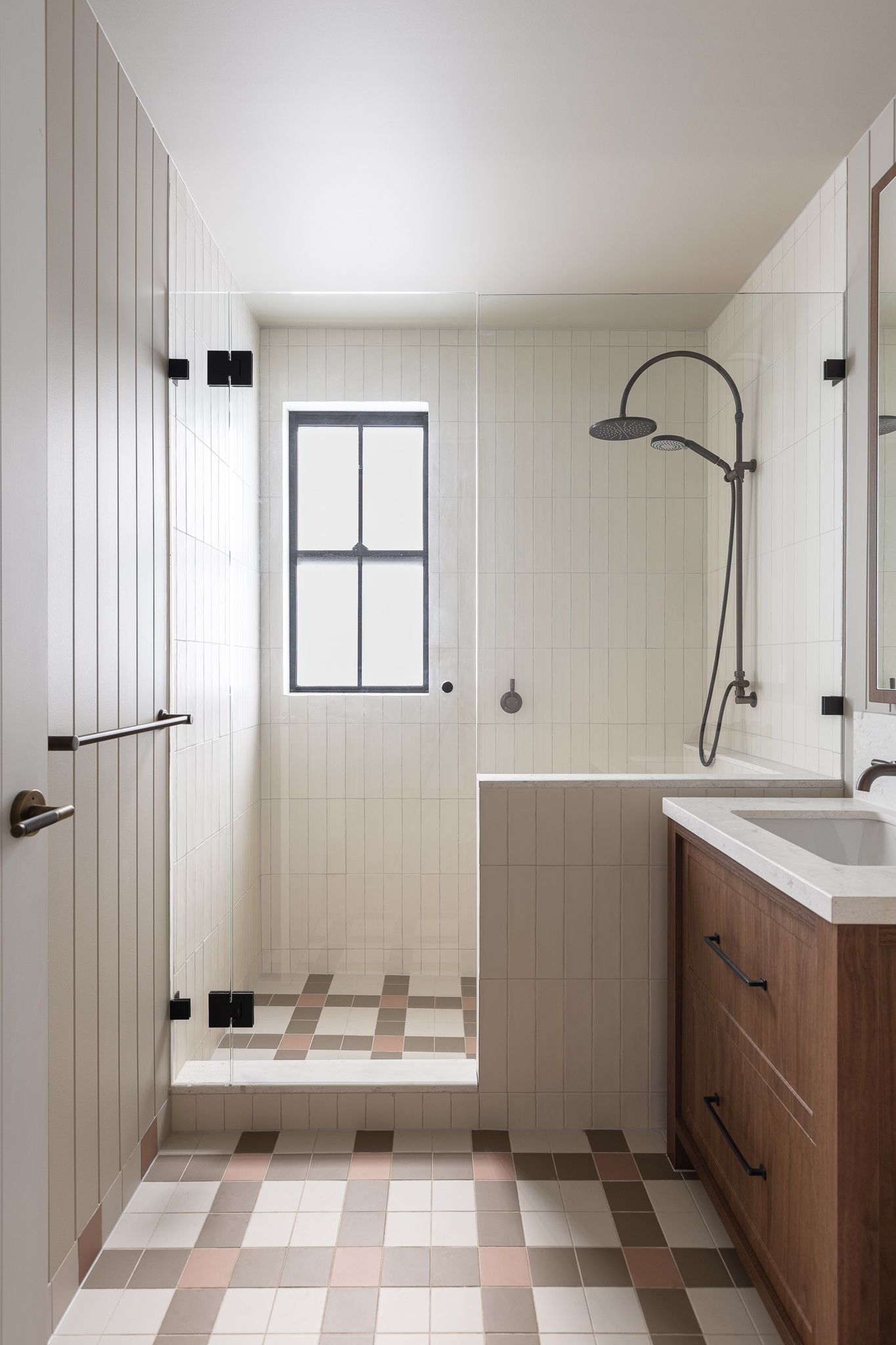 Modern bathroom interior with white vertical paneling and geometric brown and white tile floor pattern.