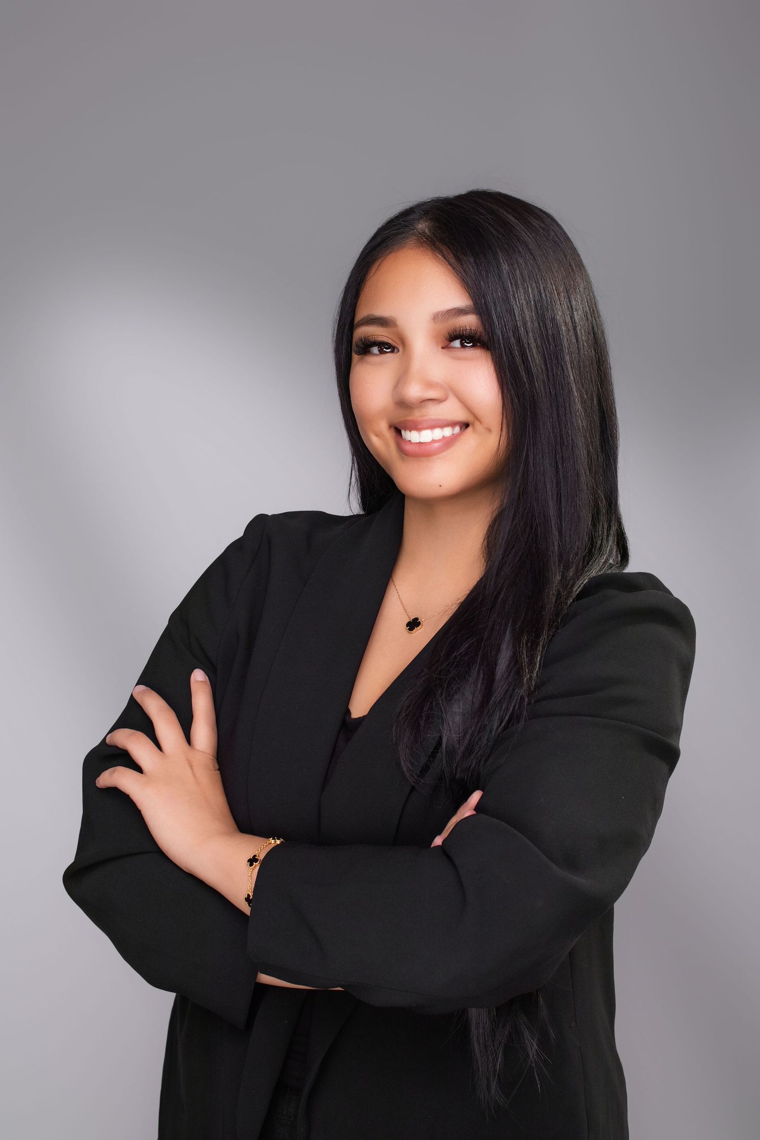 Professional portrait of woman in black blazer against gray background.