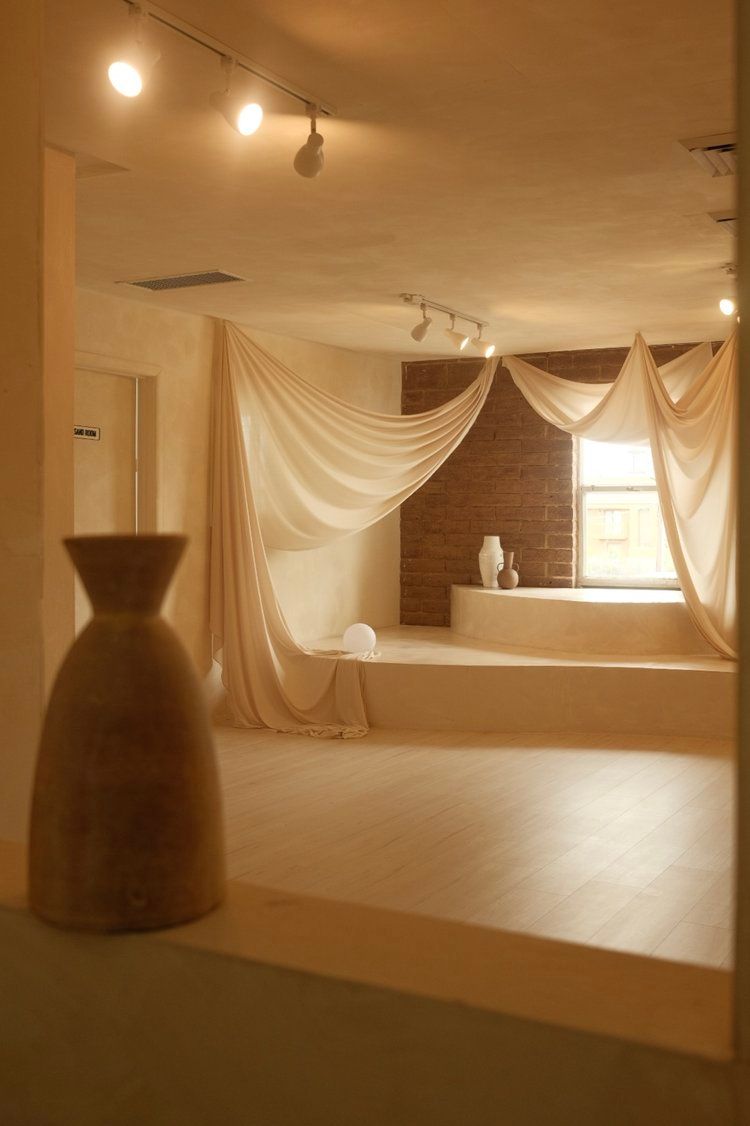 Minimalist studio space with flowing white fabric drapes and track lighting.