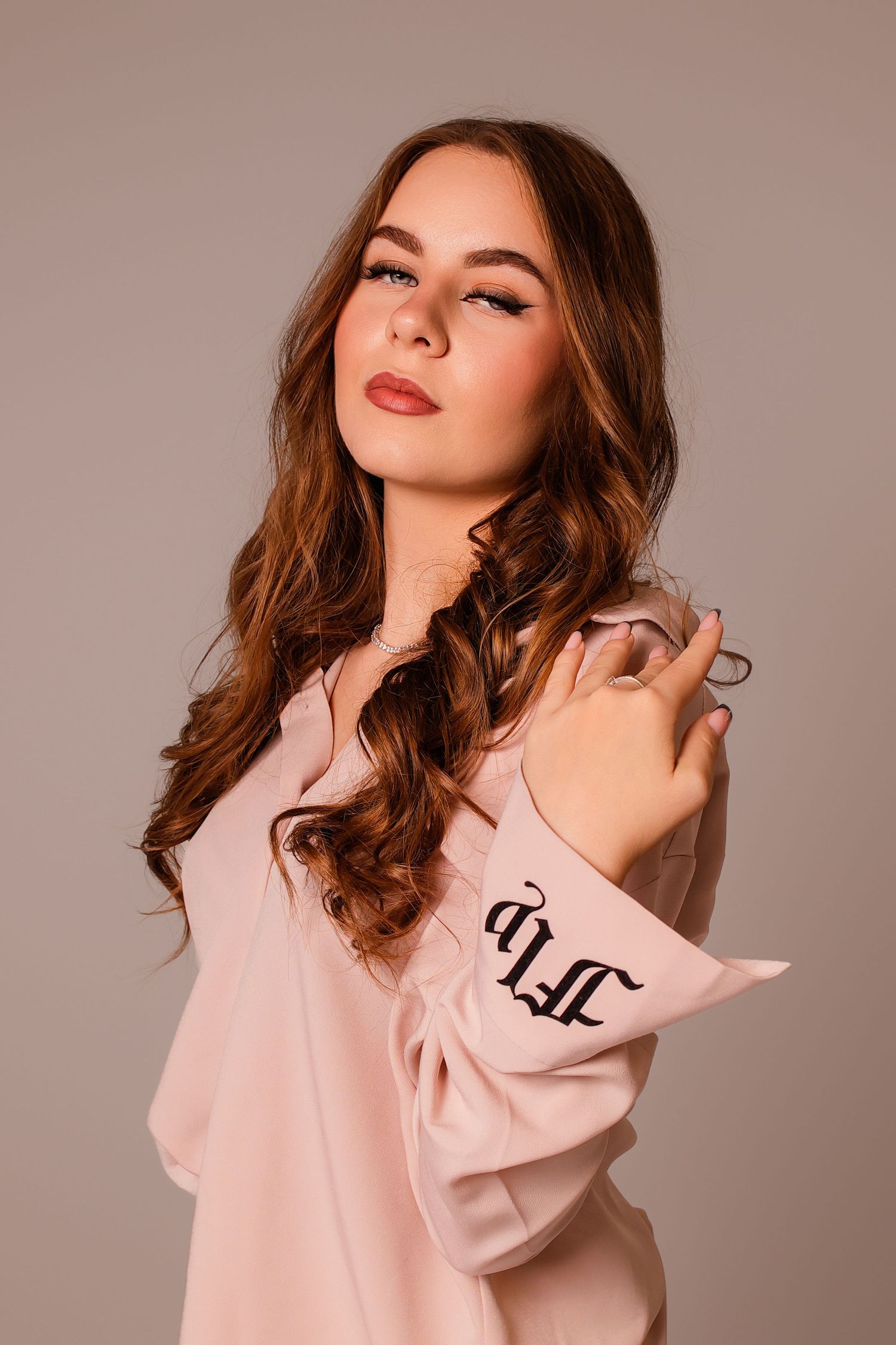 Fashion portrait in soft lighting wearing pink sweater against neutral backdrop.