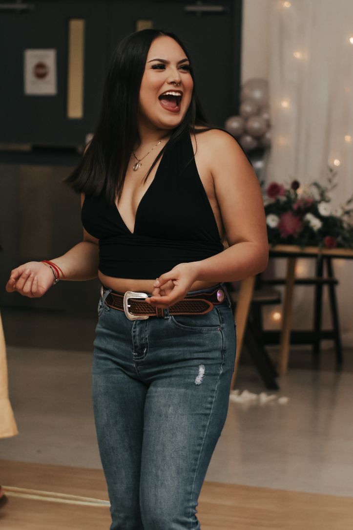 Happy expression captured in casual attire against a softly lit indoor setting.