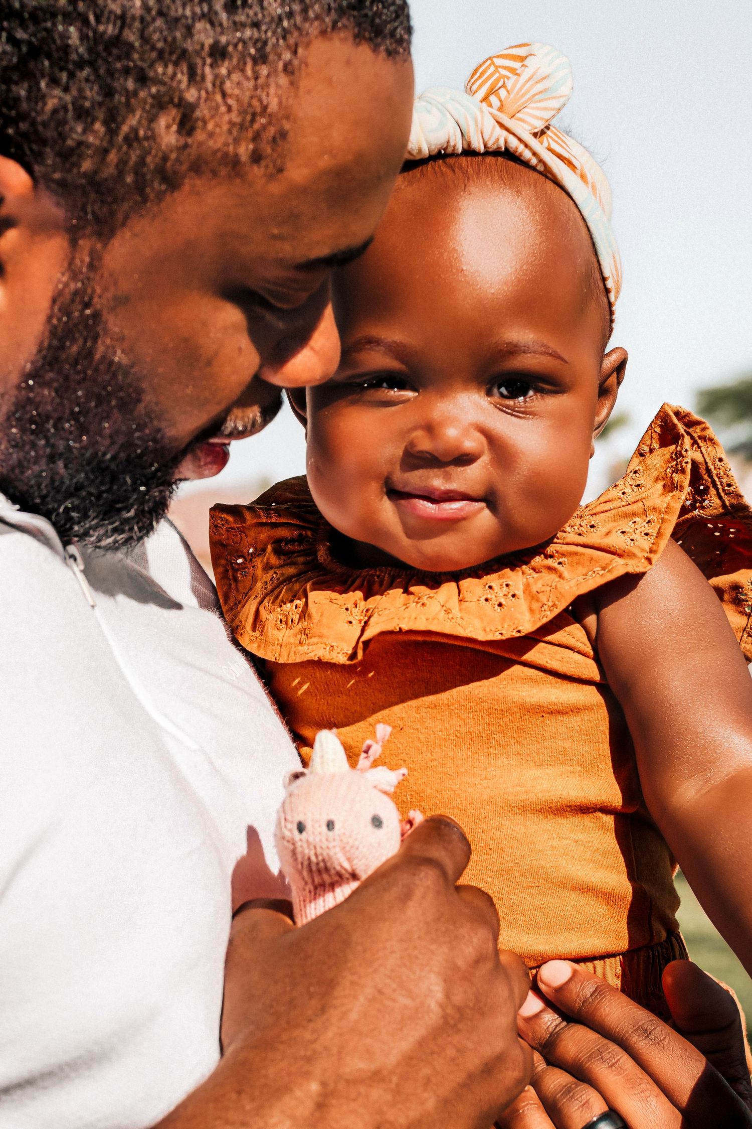 Tender moment between parent and child wearing orange outfit outdoors.