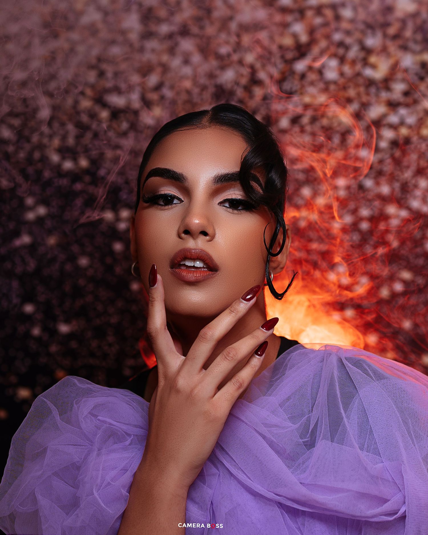 Fashion portrait featuring dramatic purple tulle fabric against a bokeh background with warm orange lighting effects.