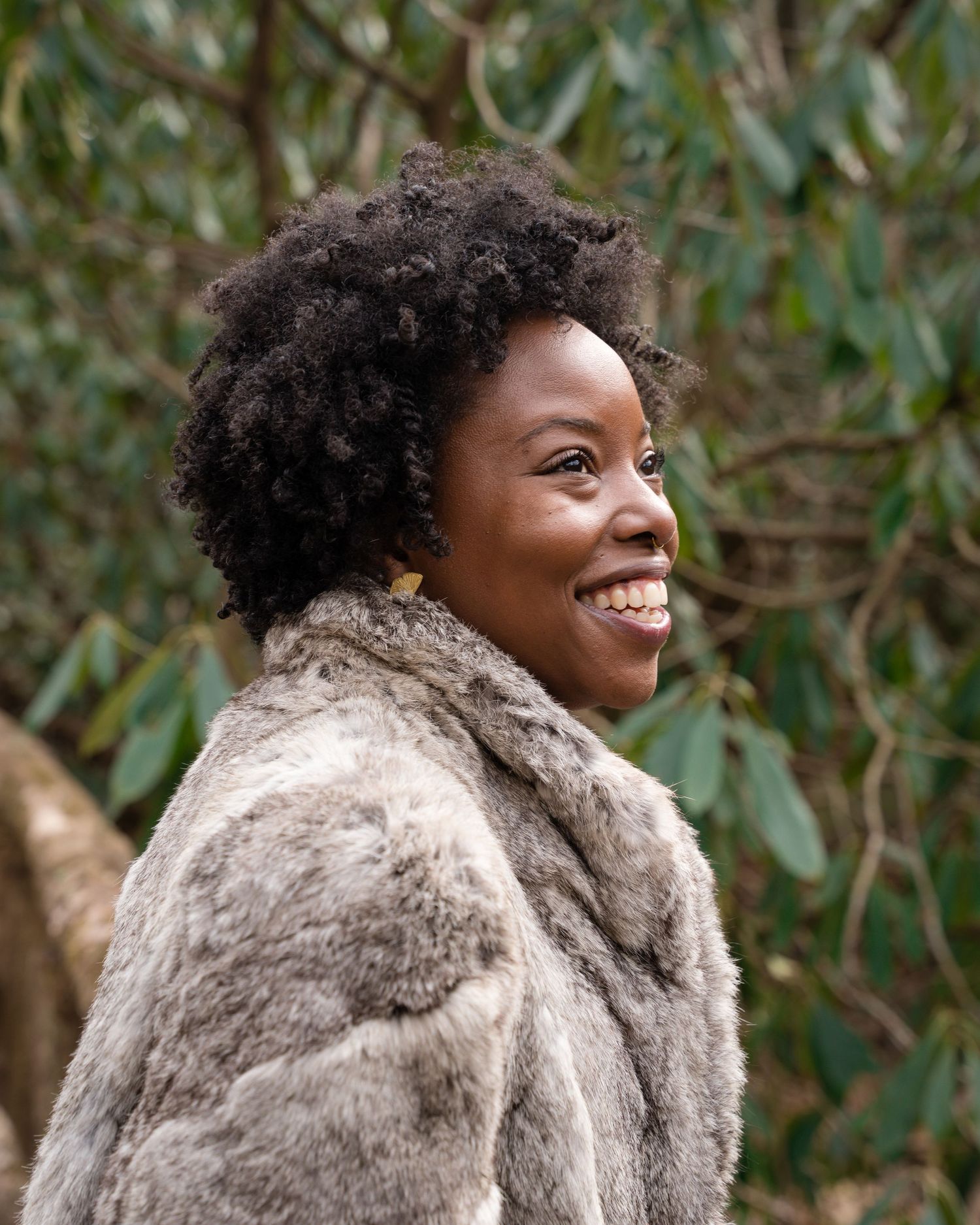 african american woman smiling in a fur coat in the forest of the blue ridge mountains north carolina