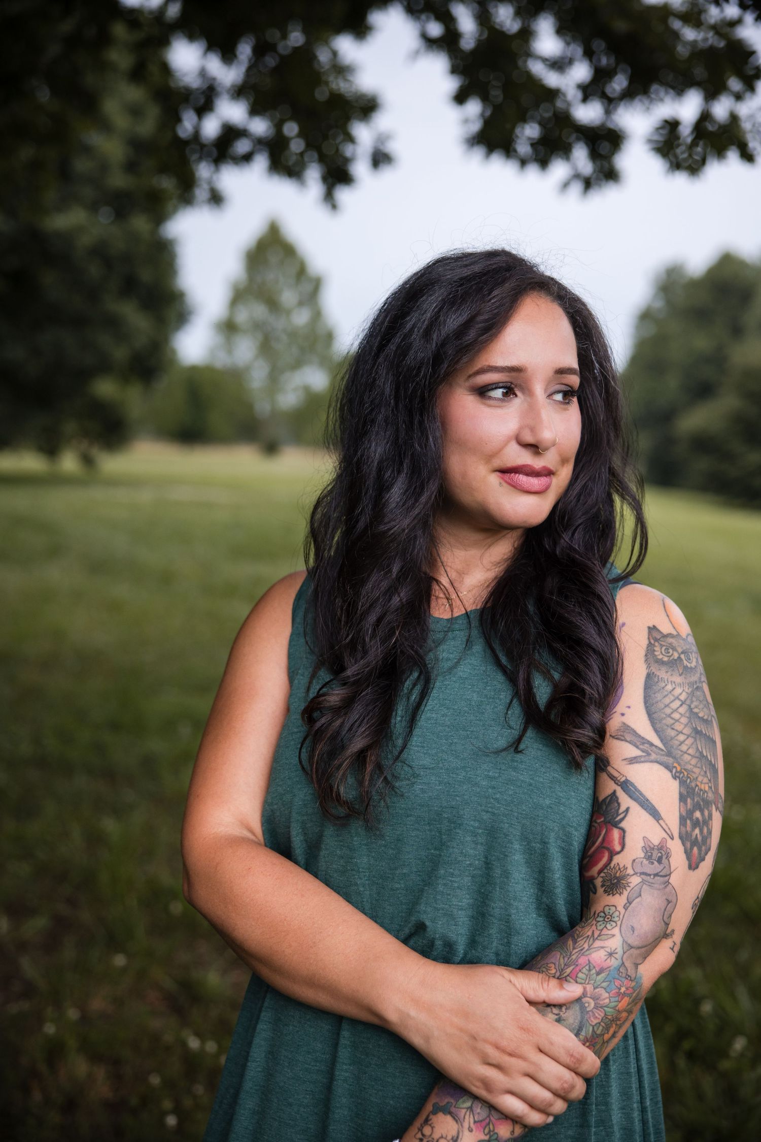 portrait of mixed latina woman with tattoos and smile on her face in a field in south carolina