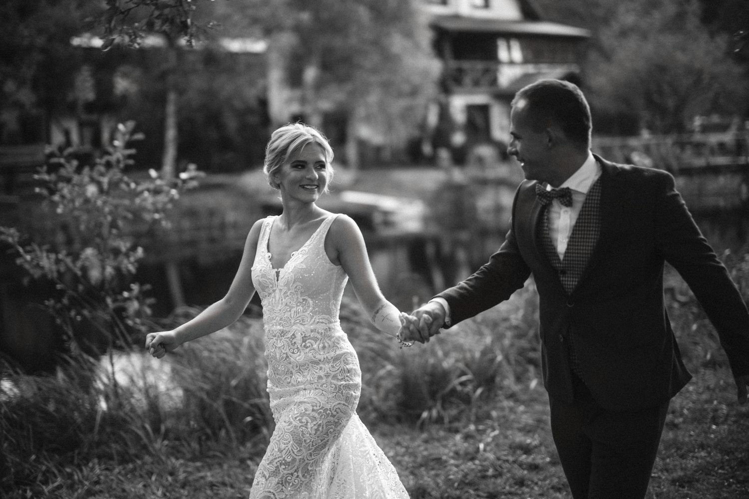 Black and white wedding portrait of couple walking through garden setting.