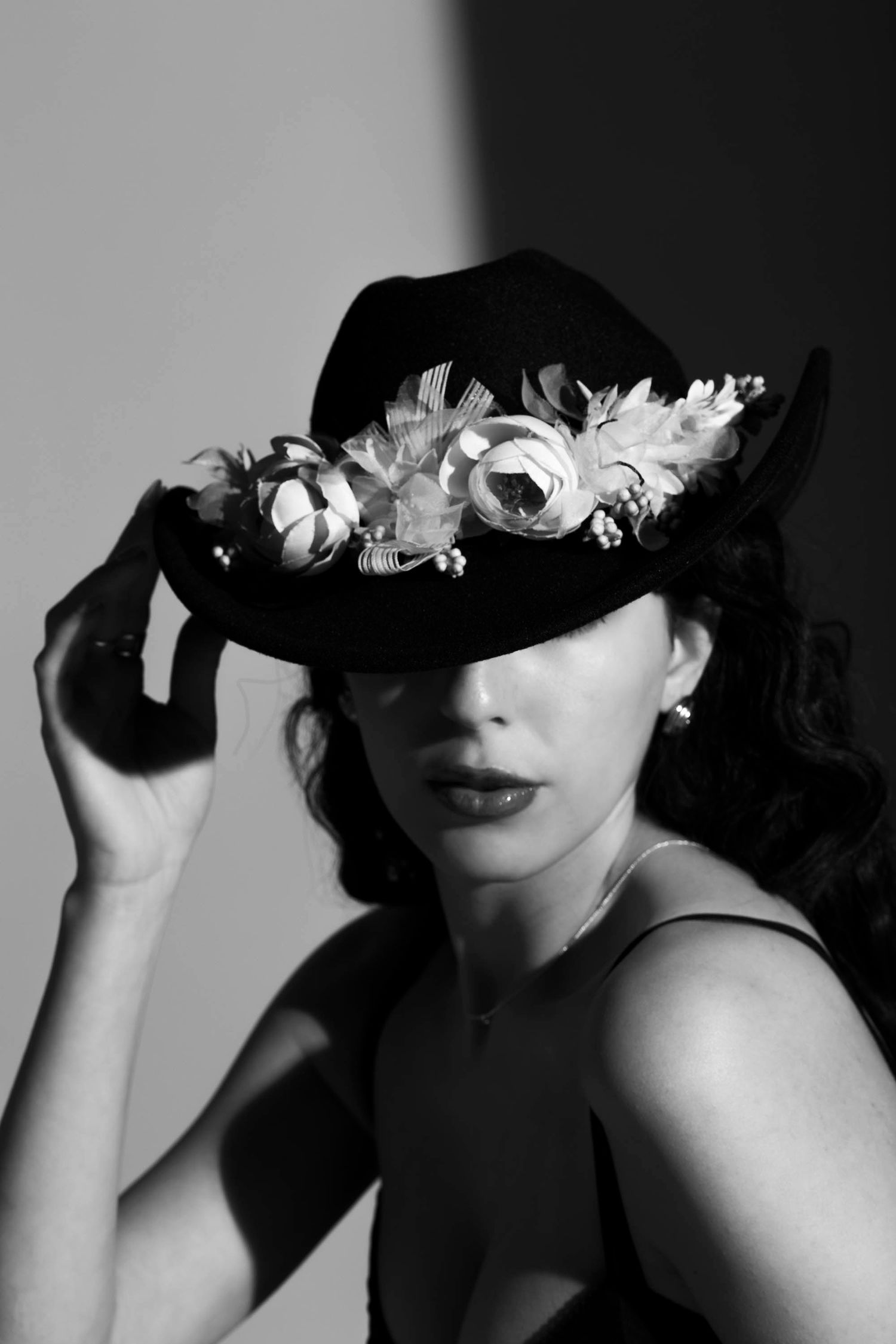 Checkerboard Black and white portrait of woman in floral hat, dramatic lighting and vintage-inspired fashion styling.