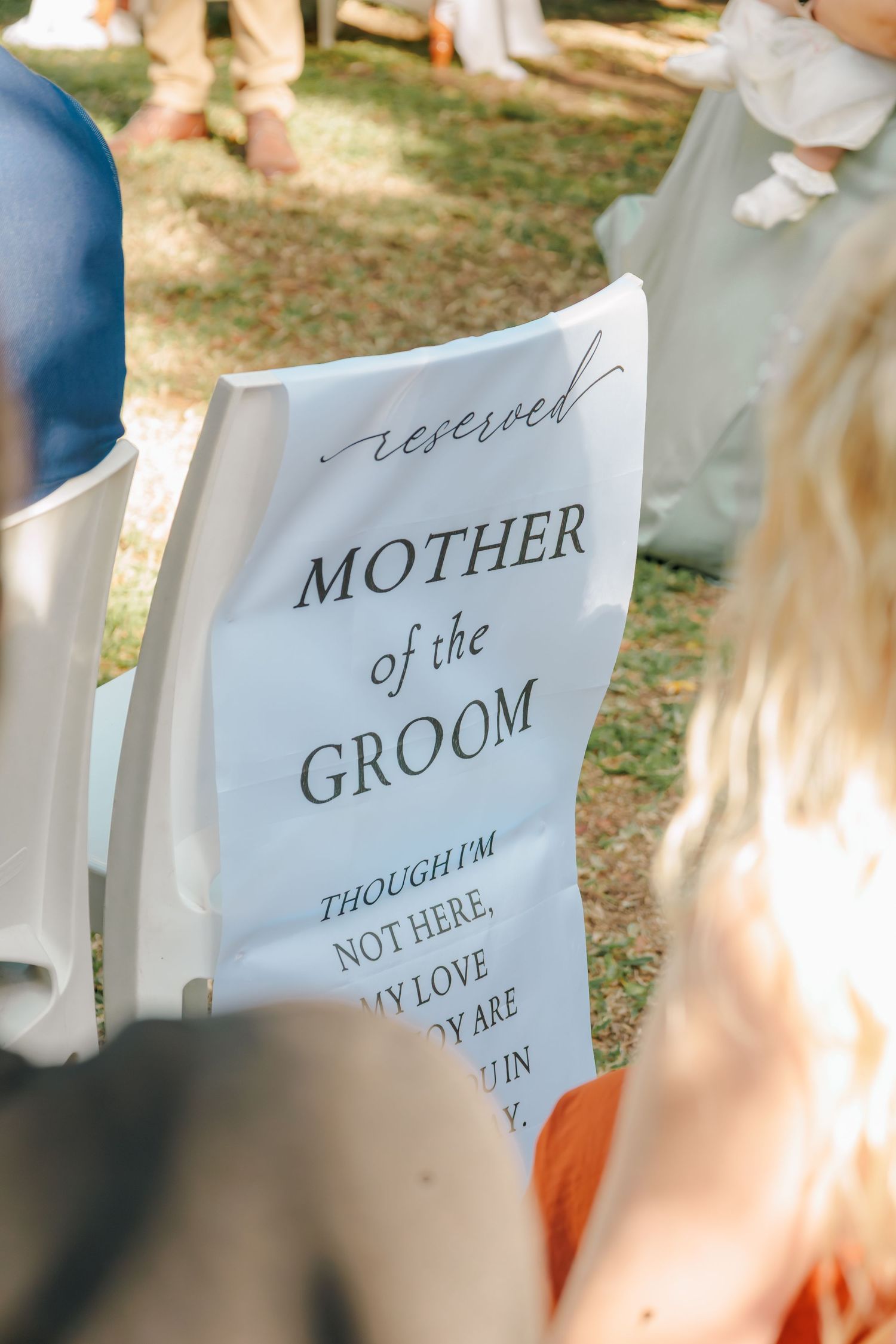 Reserved Mother of the Groom memorial chair sign at outdoor wedding ceremony seat.