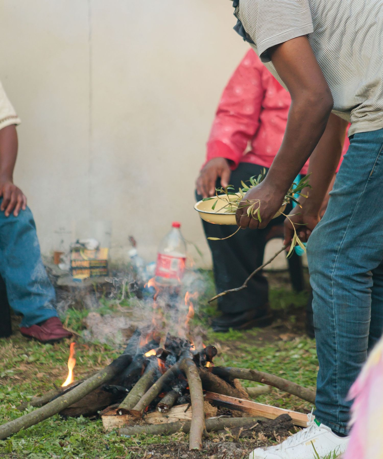 Traditional African wedding ceremony with person holding herbs over a sacred fire during ancestral ritual.