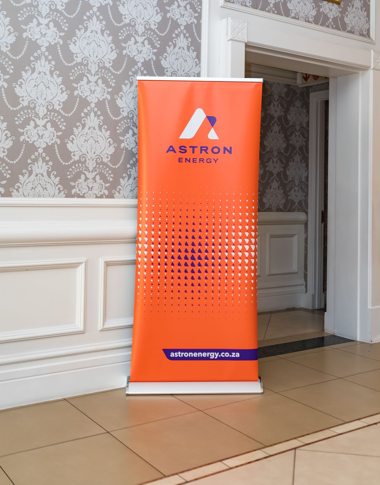 Orange Astron Energy branded pull-up banner displayed in elegant venue entrance.