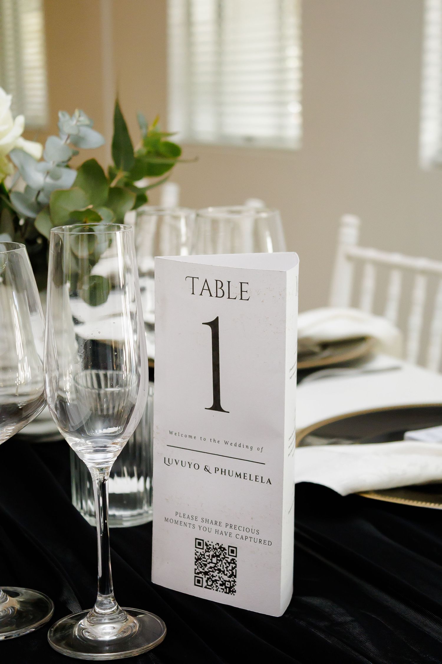 Wedding Table 1 card for Luvuyo and Phumelela with QR code beside champagne flute.