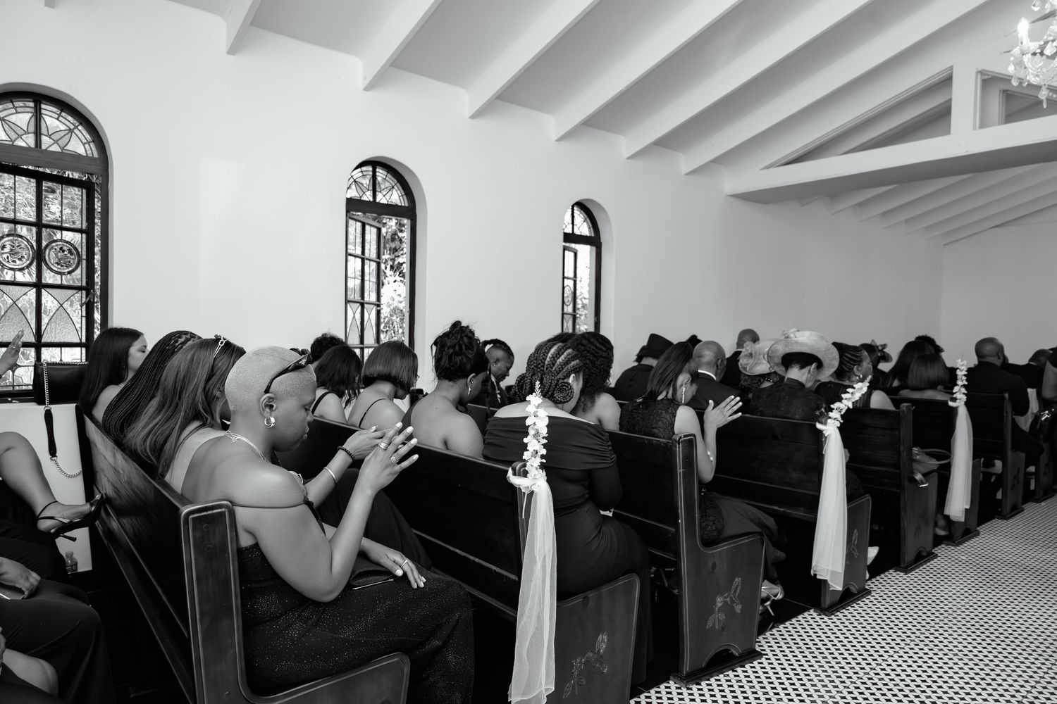 Black and white photo of wedding guests seated in church pews during ceremony.