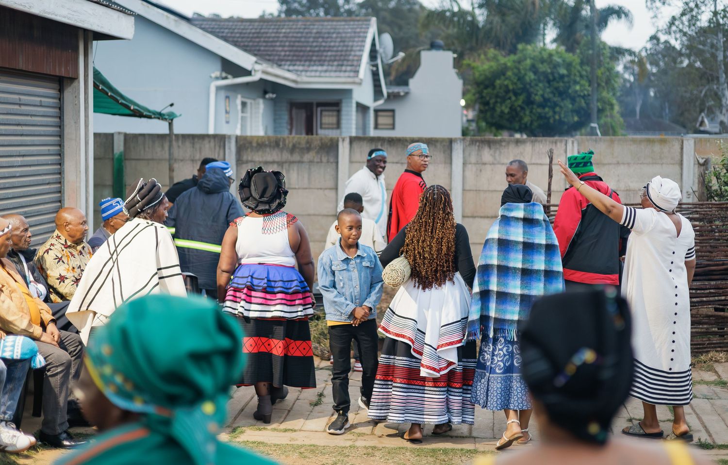 Group of people in traditional African clothing holding hands in a circle during a ceremony.