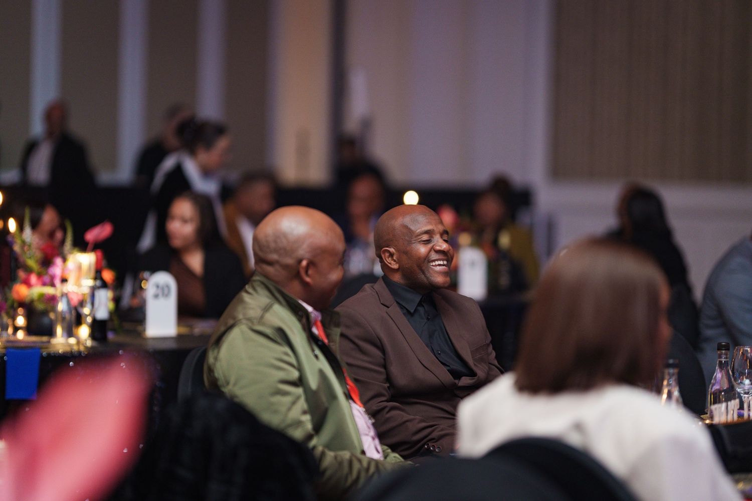 Two men laughing together at a Beyond Energy corporate dinner event.