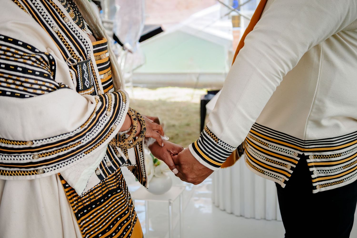 Couple in traditional Xhosa attire holding hands during a cultural wedding ceremony.
