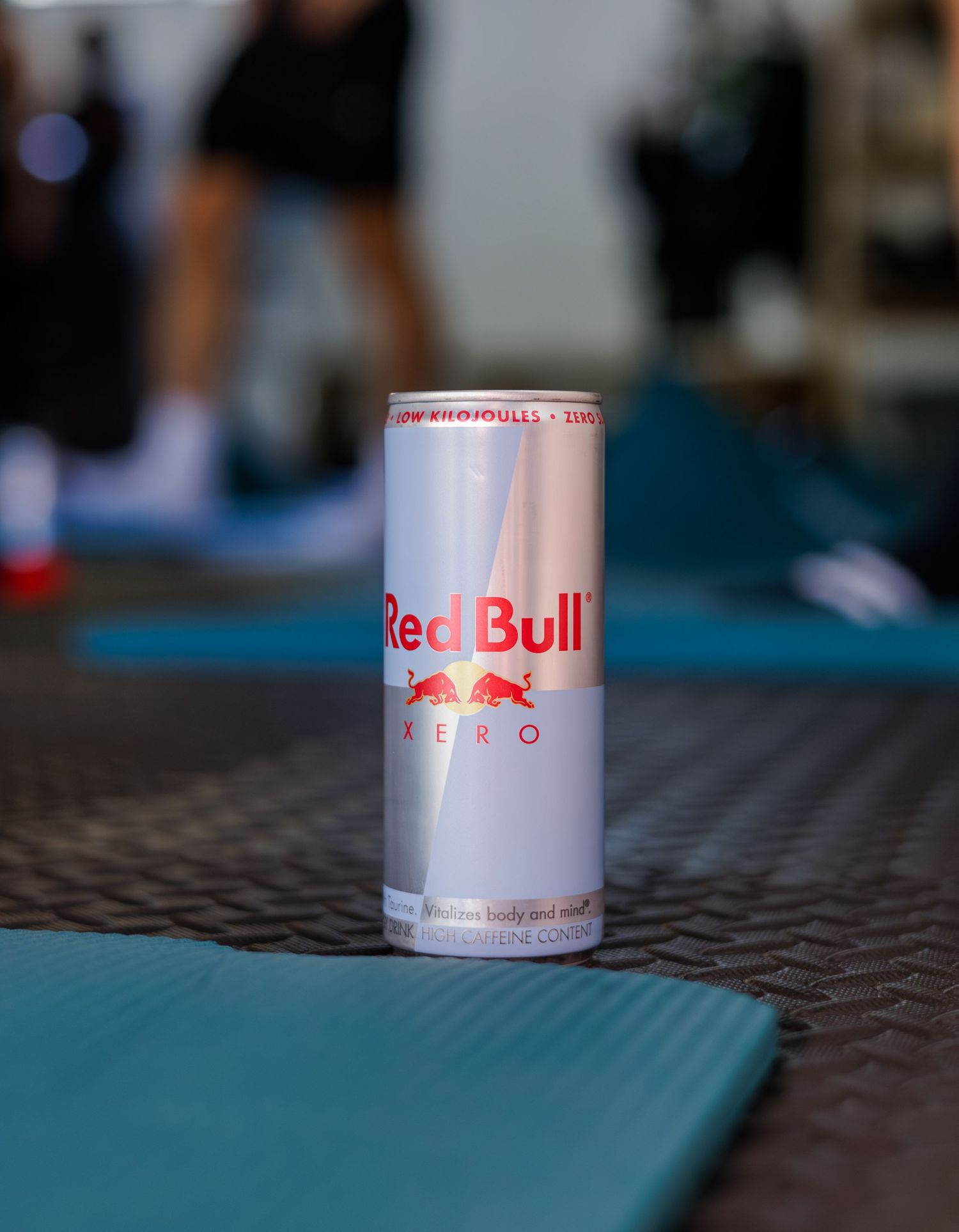 Red Bull Zero energy drink can placed on a blue gym mat in a fitness center.