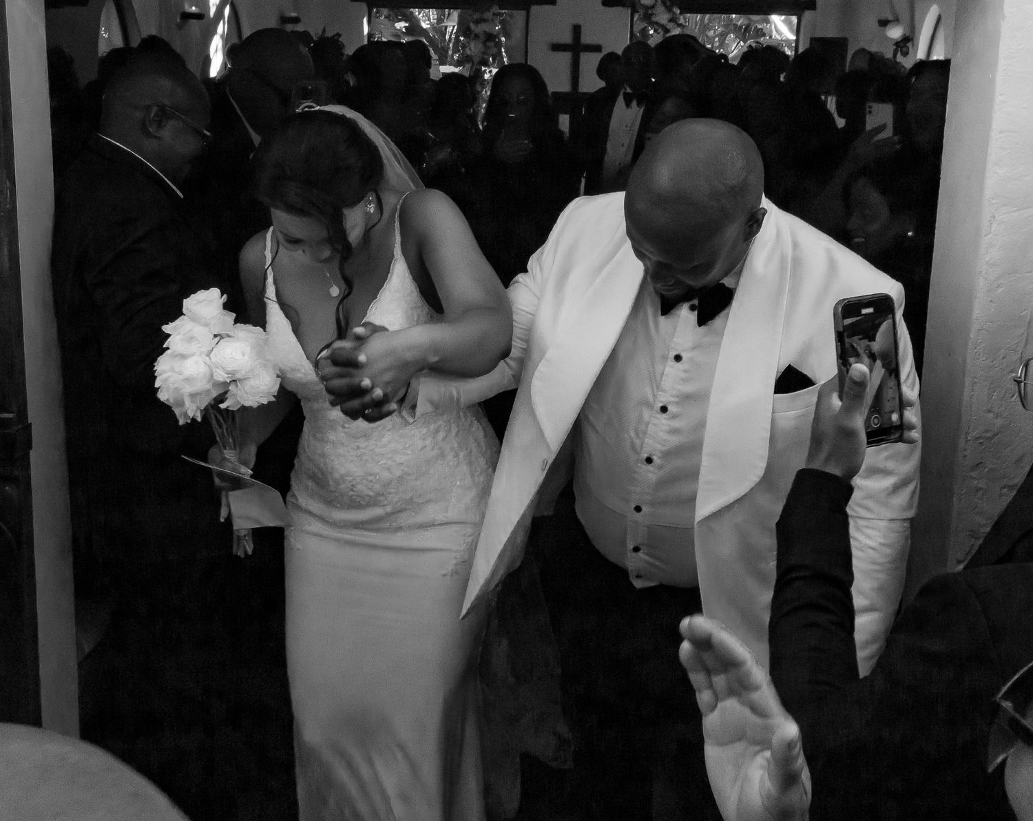 Black and white photo of a bride and groom exiting a crowded church after ceremony.