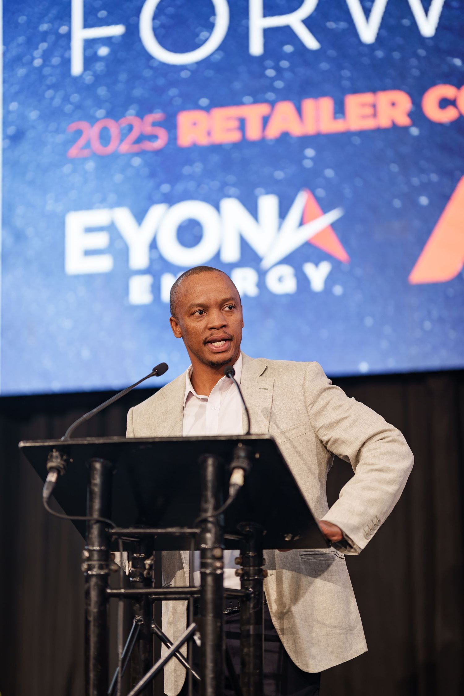 Speaker presents at podium during 2025 Eyona Energy Retailer Conference event.