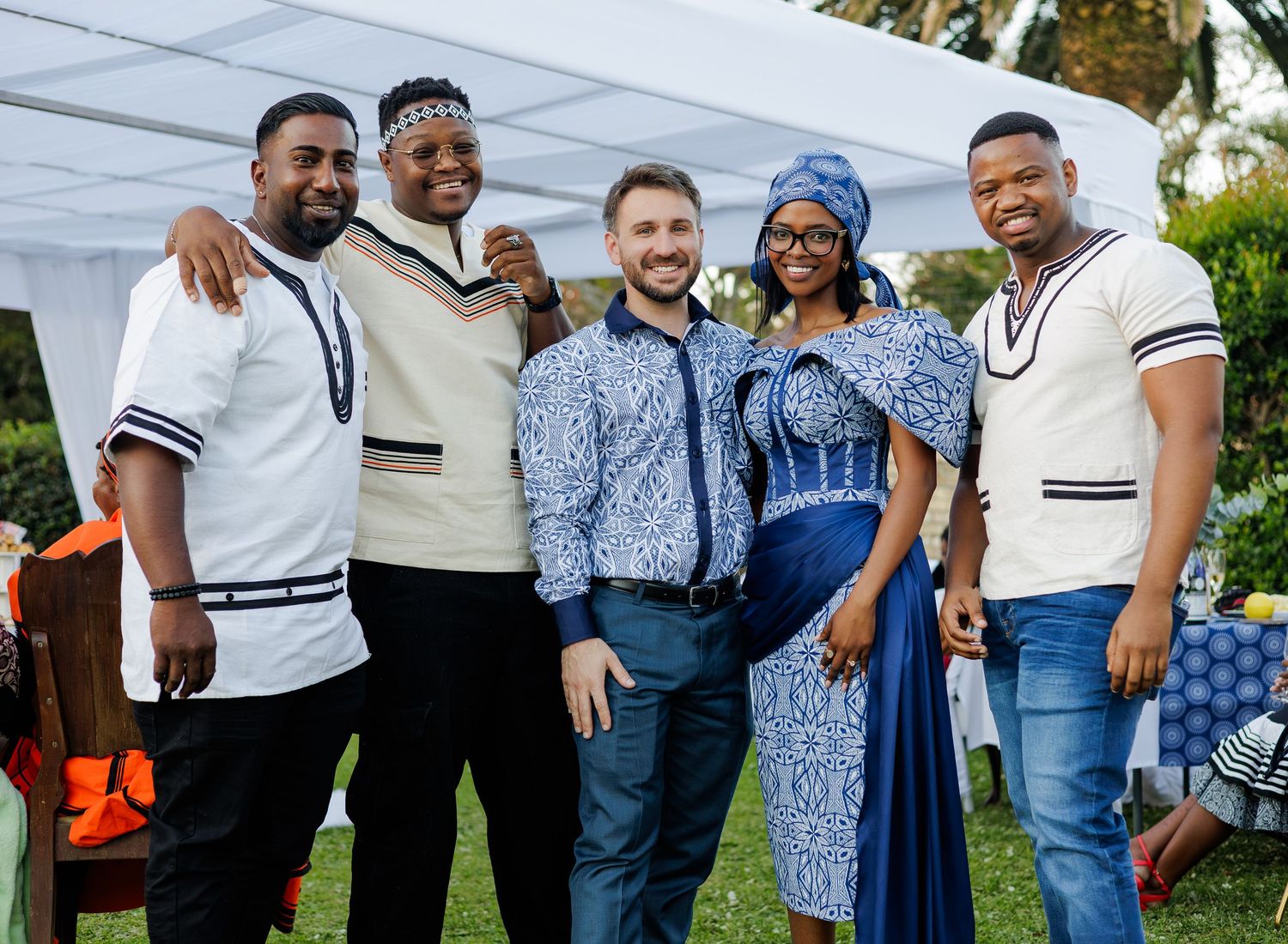 Group of five friends posing together at a traditional African celebration, wearing blue and white Ndebele print outfits.